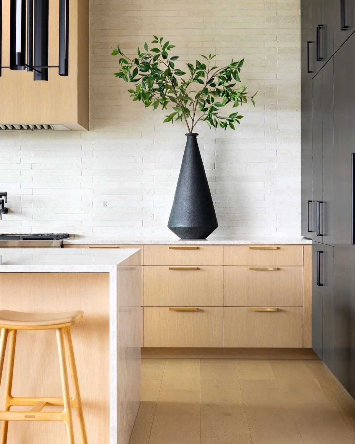 We layered soft wood tones, subtle texture, and sculptural elements to create a kitchen that feels both grounded and refined. The oversized vessel and greenery moment are just enough drama without disrupting the calm. #AustinInteriorDesign #ATXInteri