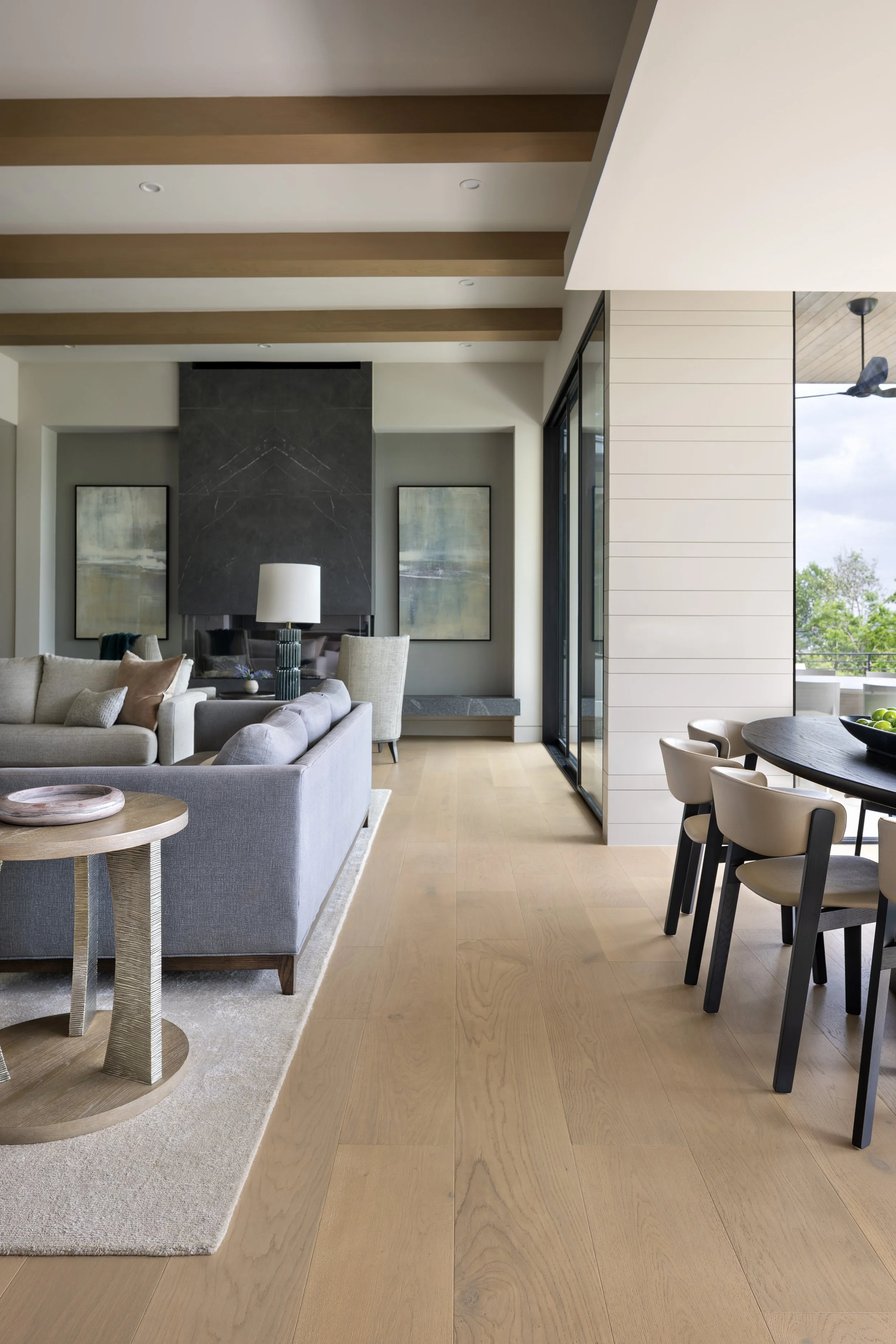 Wide-plank wood flooring flowing through the Graphic Modern dining and living spaces by Marion Interior Design.