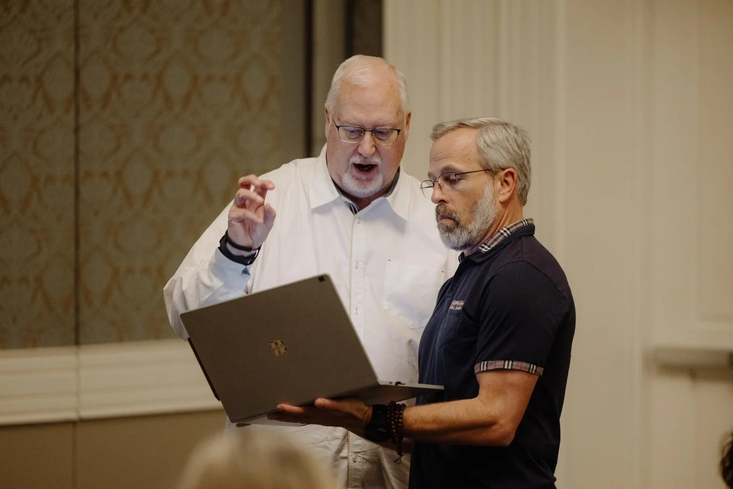 Mike Ferrell in a white shirt coaches a leader as they look over a laptop together