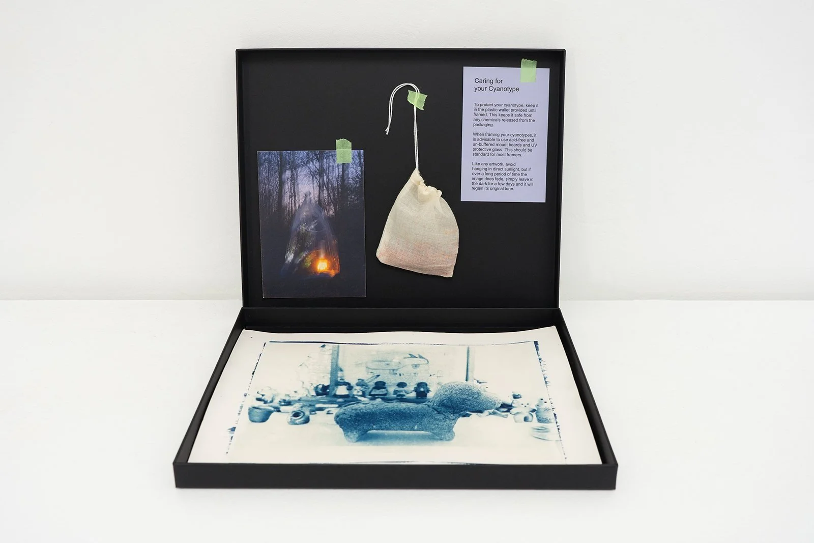 Example of a Grief Commission cyanotype, by visual artist Harri Harrison. It is in an open, black display-box accompanied by a handmade teabag, complimentary postcard and care instructions.