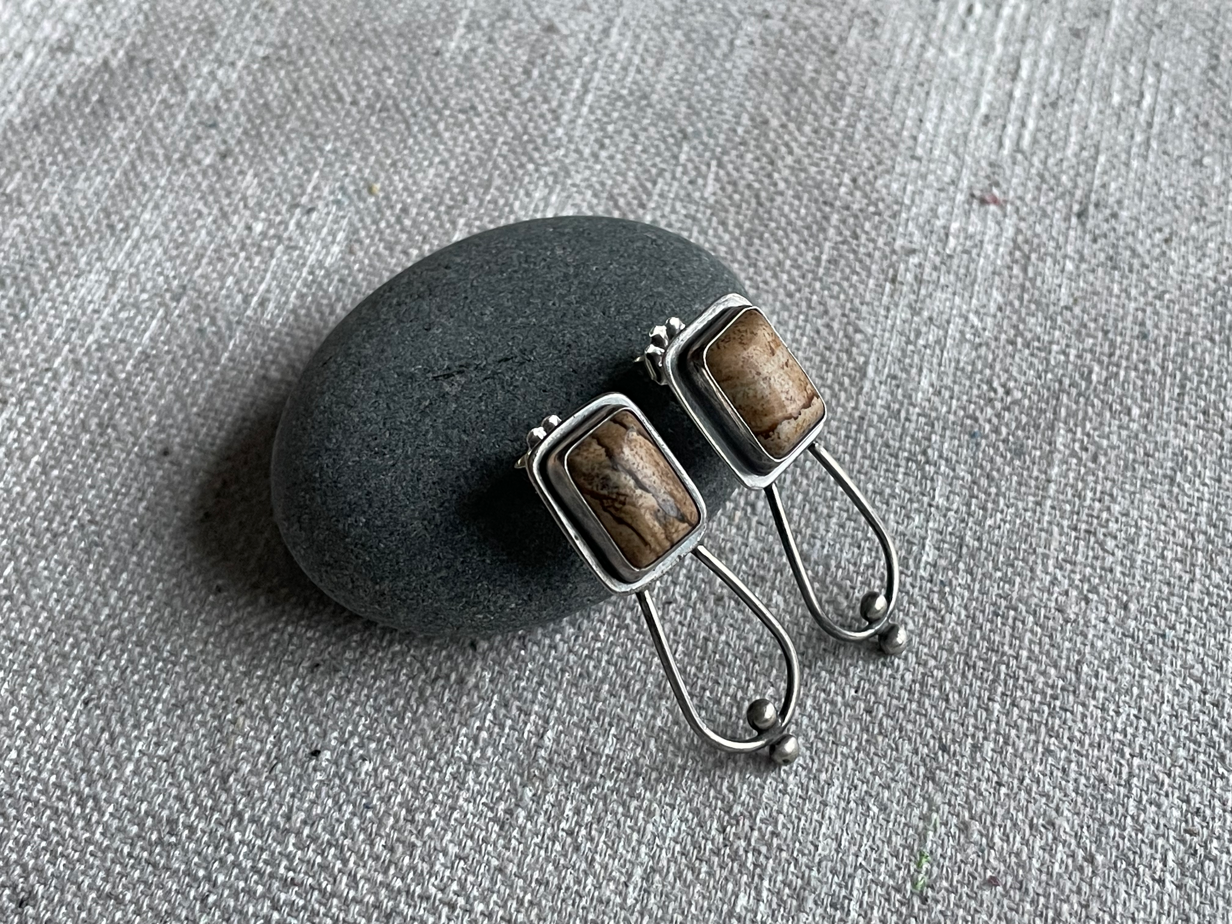 A close-up photo of a black stone, a pair of sunglasses with marble-like frames resting on it, on a textured gray surface.