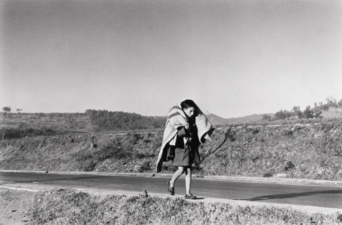 Boy carrying blanket over his shoulders, on the road from Barcelona to the French border