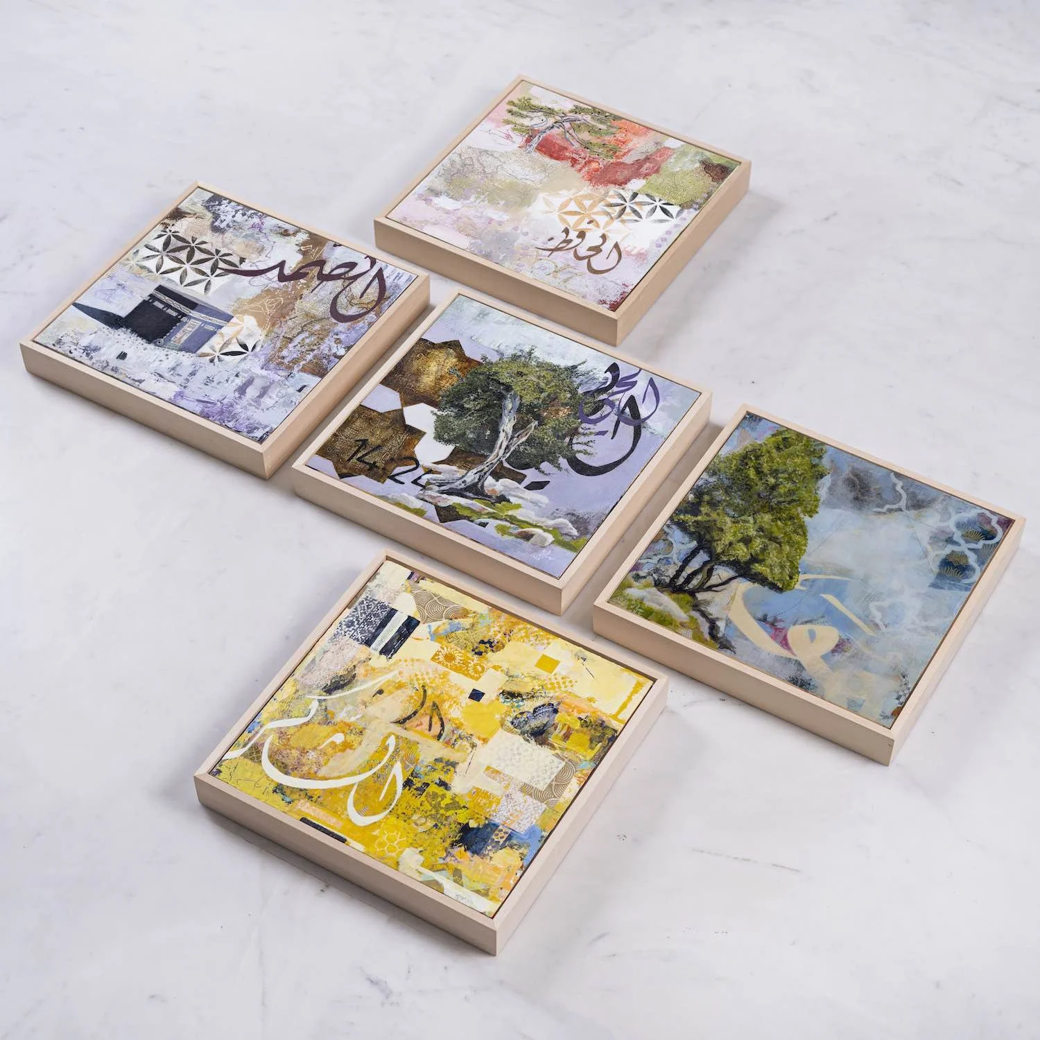 Five framed paintings from the Hu Collection arranged on white marble, including the Kaaba and three tree motifs, with Arabic calligraphy, mixed media on panel by Sara Kabariti