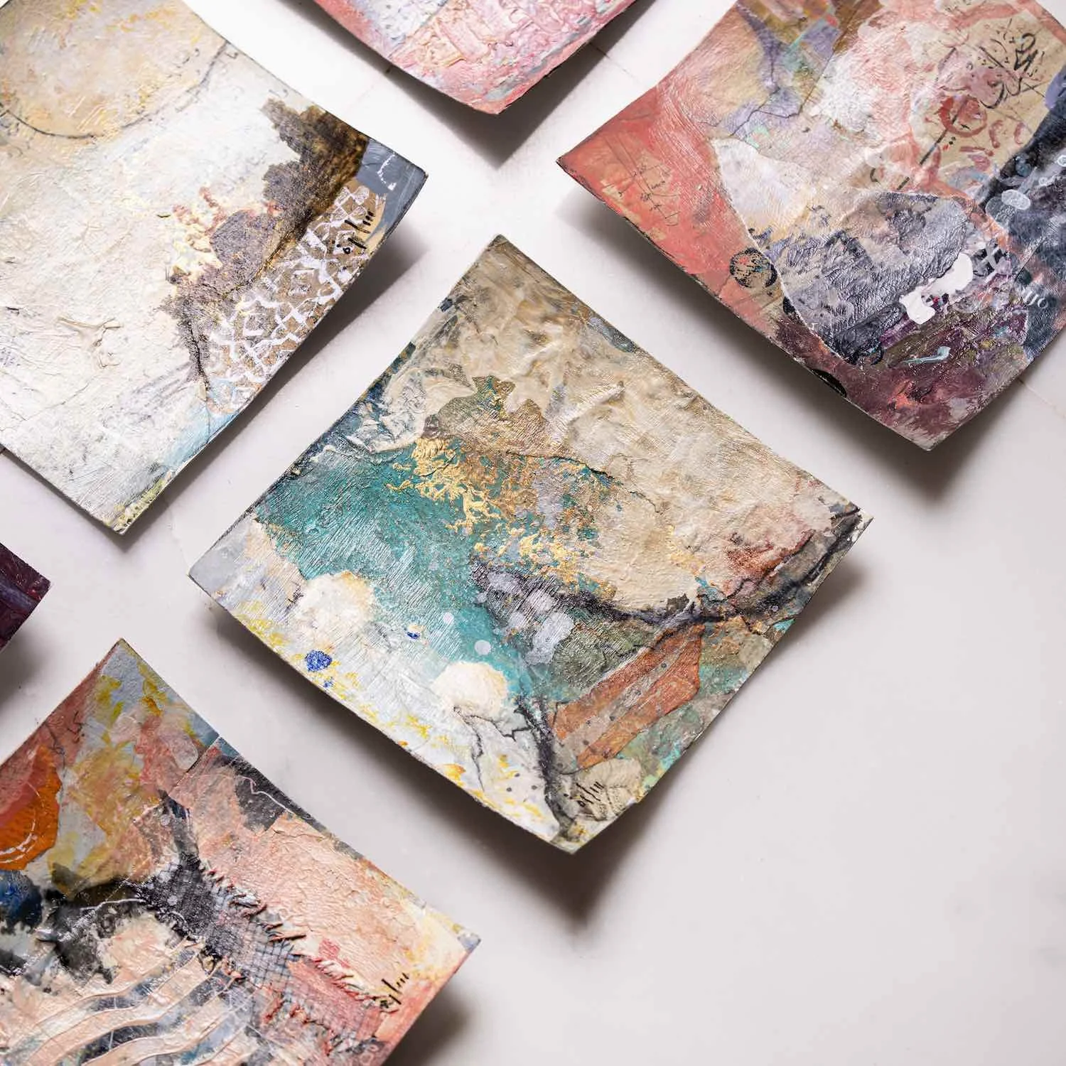 Miniature mixed media paintings from the Athar Collection laid out together on white marble