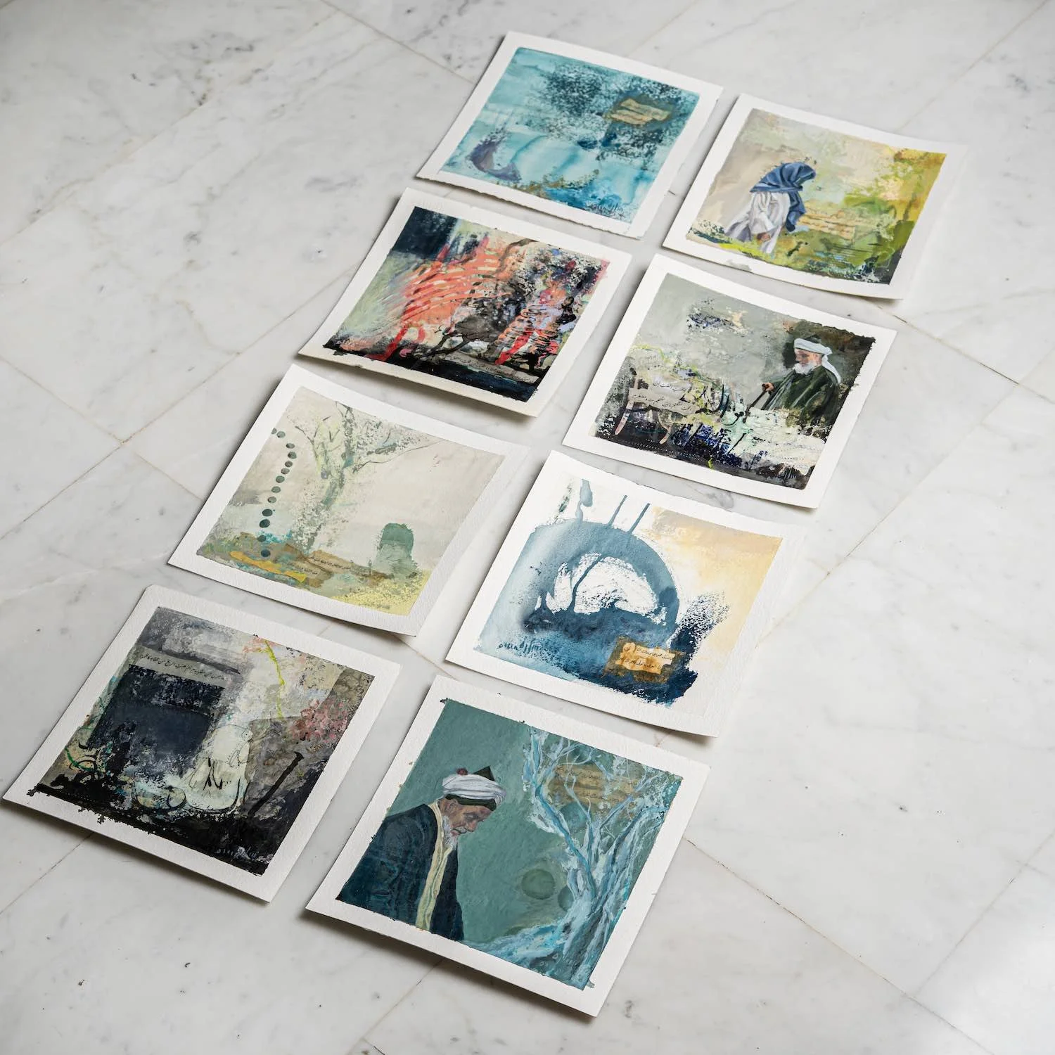 Eight unframed paintings from the Burda Collection laid out on marble, by Sara Kabariti
