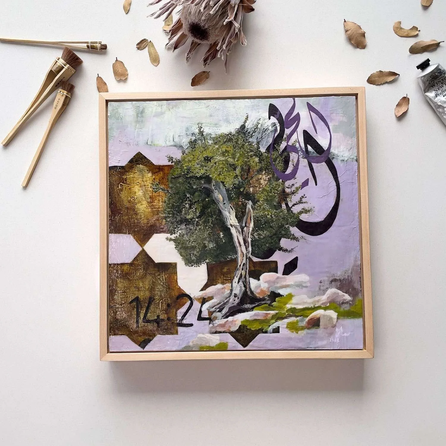 Perpetual, framed mixed media painting depicting Al-Hay in Arabic calligraphy, a tree rooted among stones with the reference 14:24, Hu Collection 2023, by Sara Kabariti, styled in a flatlay
