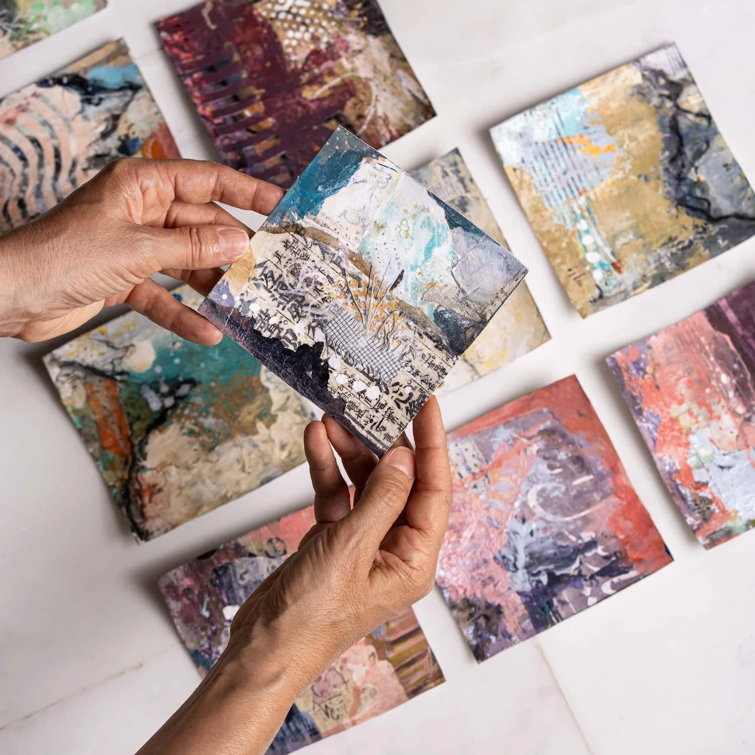Tafakkur, a 12 x 12 cm miniature painting from the Athar Collection, held in Sara Kabariti's hands above the rest of the collection laid out on marble