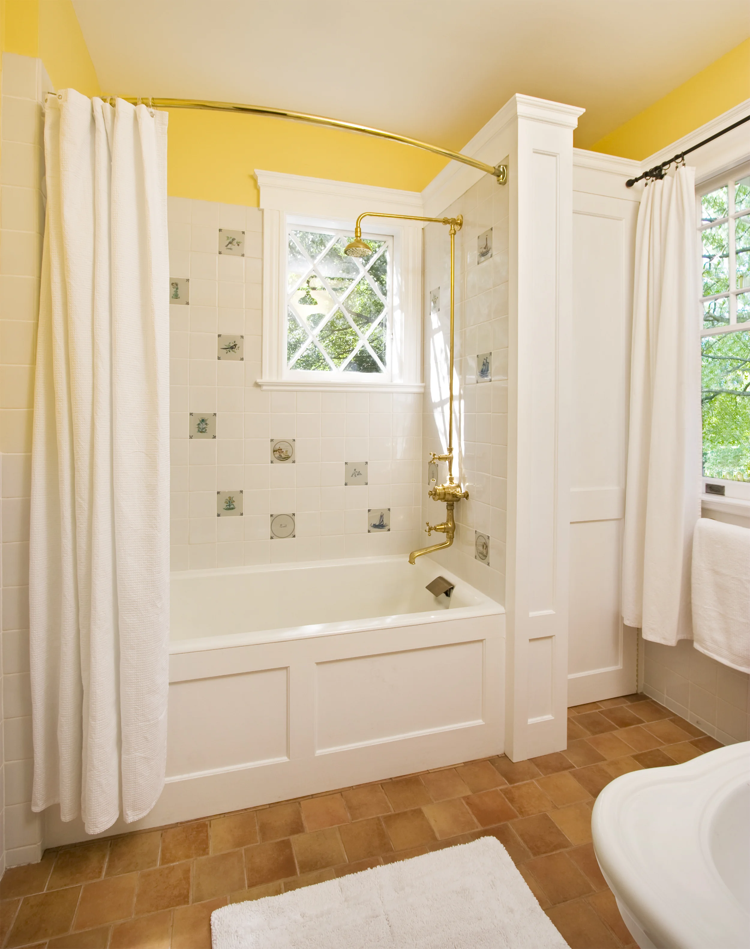 The renovated third floor bathroom features exposed plumbing, a window original to the home and Hand Painted Delft Ceramic Tiles as well as custom millwork and terra cotta tile floors with radiant heat.