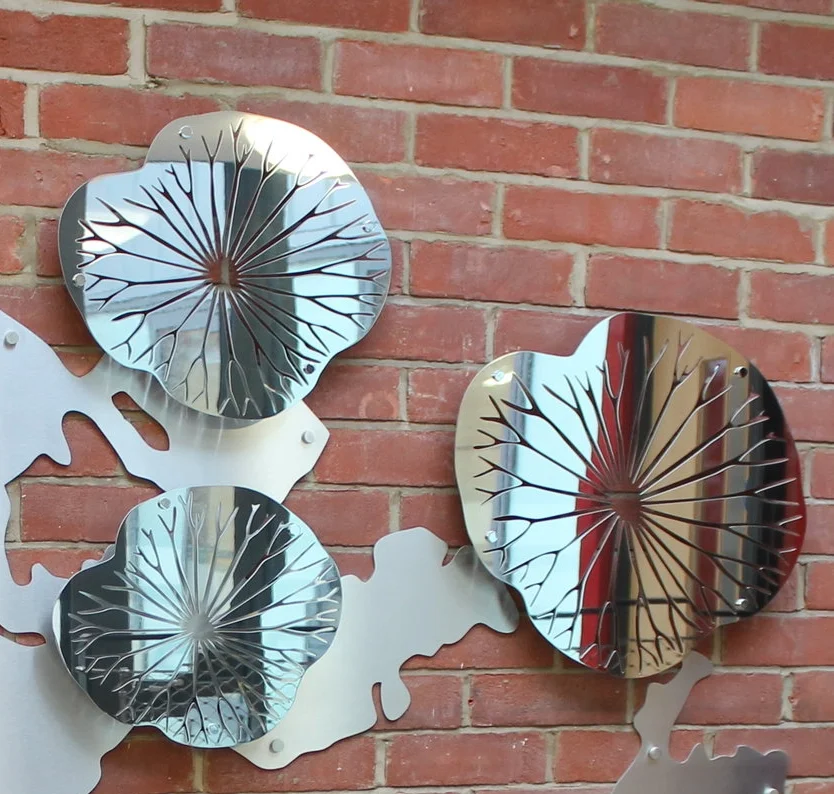 Decorative wall art with mirrors shaped like flowers, mounted on a red brick wall.