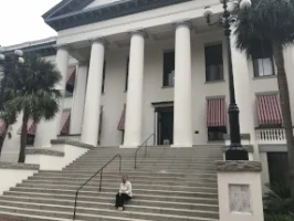 Jen Ross sits on the steps of Florida's State Capitol building in Tallahassee, FL