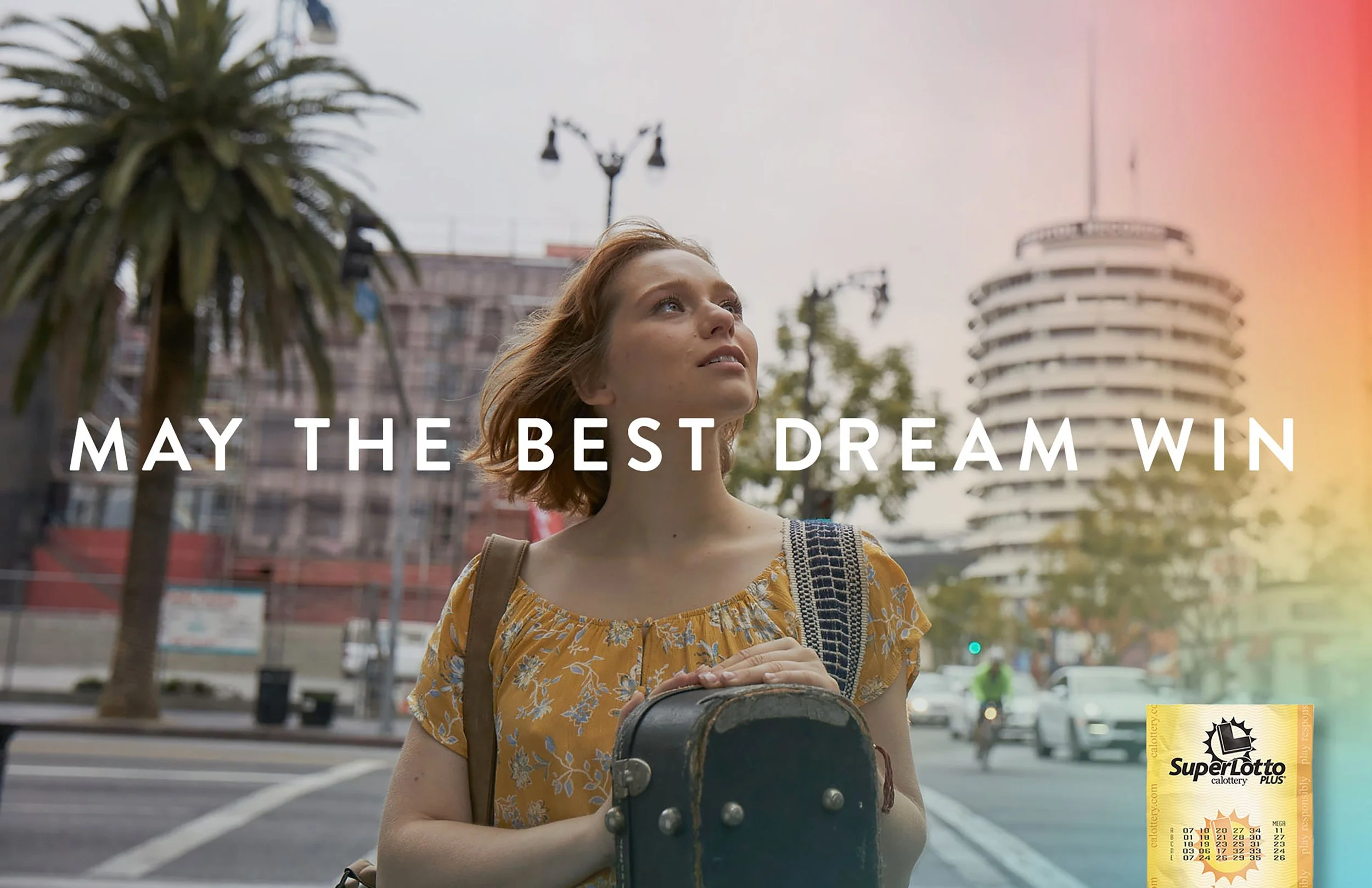 A young woman with red hair holding a skateboard, standing in an urban street scene with palm trees and buildings, and overlaid with the text "May the Best Dream Win." There is also a SuperLotto Plus ticket in the bottom right corner.