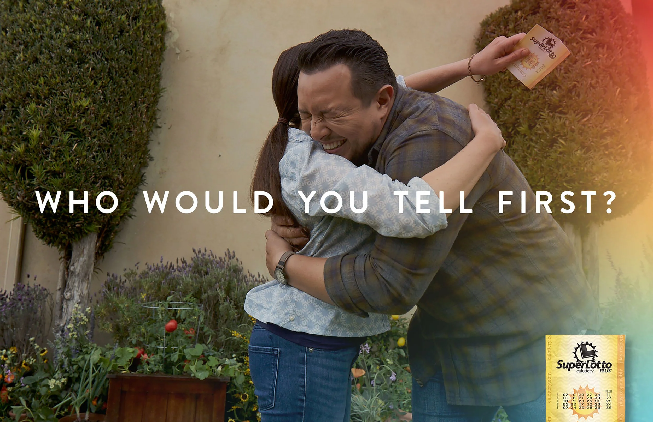 A man and woman hugging each other outdoors, with the woman holding a lottery ticket, and the text 'Who would you tell first?' in the foreground.
