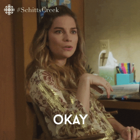 Alexis from Schitt's Creek wearing a patterned blouse in a room with a desk and colorful folders, saying "Okay that's very rude."