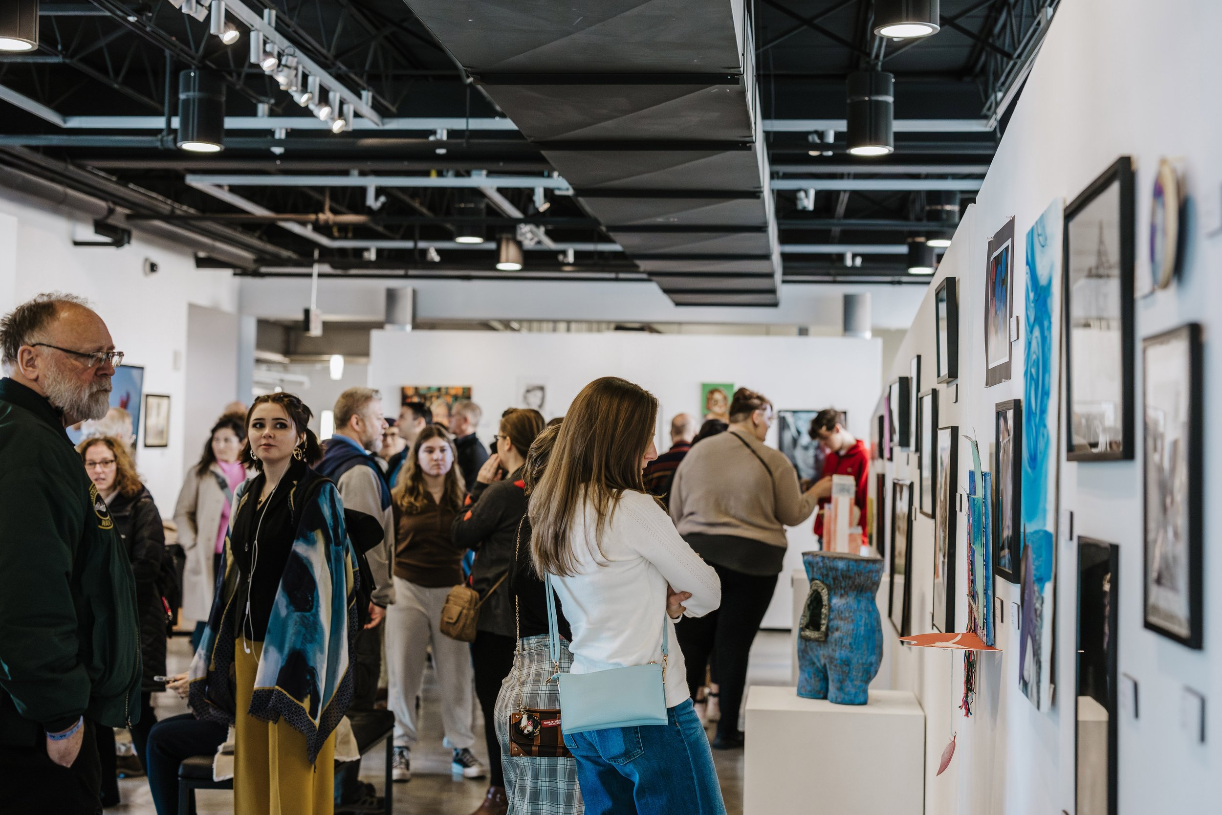 People viewing artwork at an art gallery exhibition.