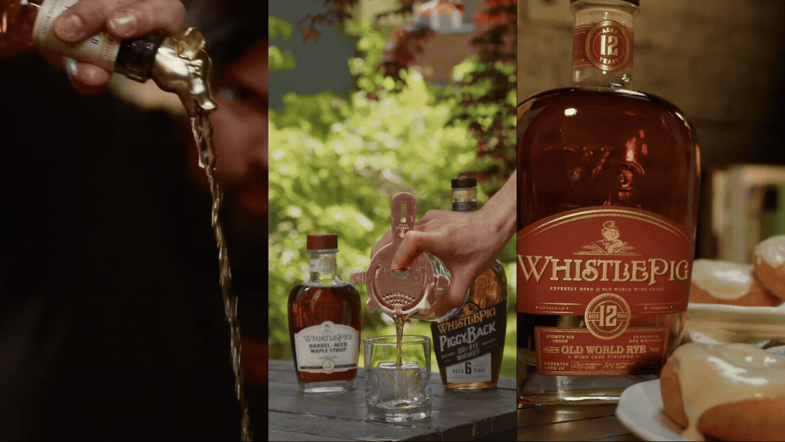 A person pouring whiskey from a bottle into a glass outside surrounded by greenery, with bottles of whiskey and small plates of cookies in the background.