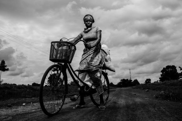 Evans Ahorsu, 2019: Amina is married with four kids. Her husband is a farmer. Amina won’t wait for her husband to come back from the farm to take some responsibilities. She picks corn, puts it in a sack on her bicycle and drives to the cornmeal machine whenever her husband is not around. She believes the sharing of labour is the best.