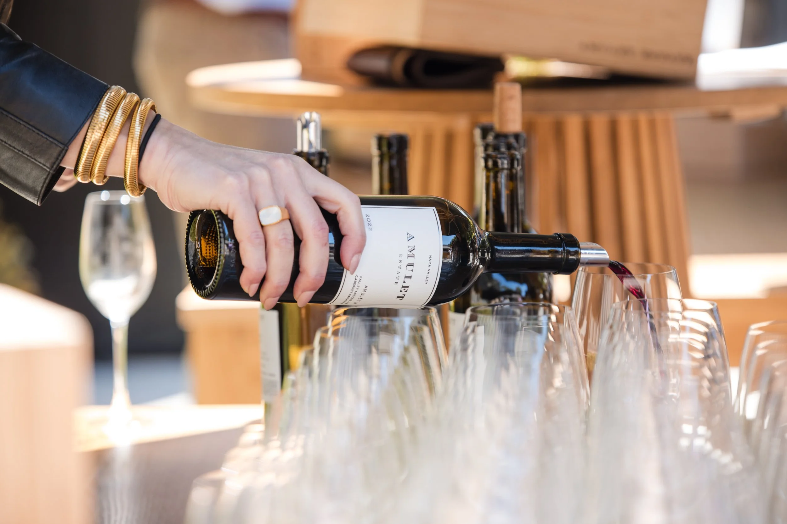 A bottle of red wine is being poured into a sea of empty wine glasses at an event in Napa Valley