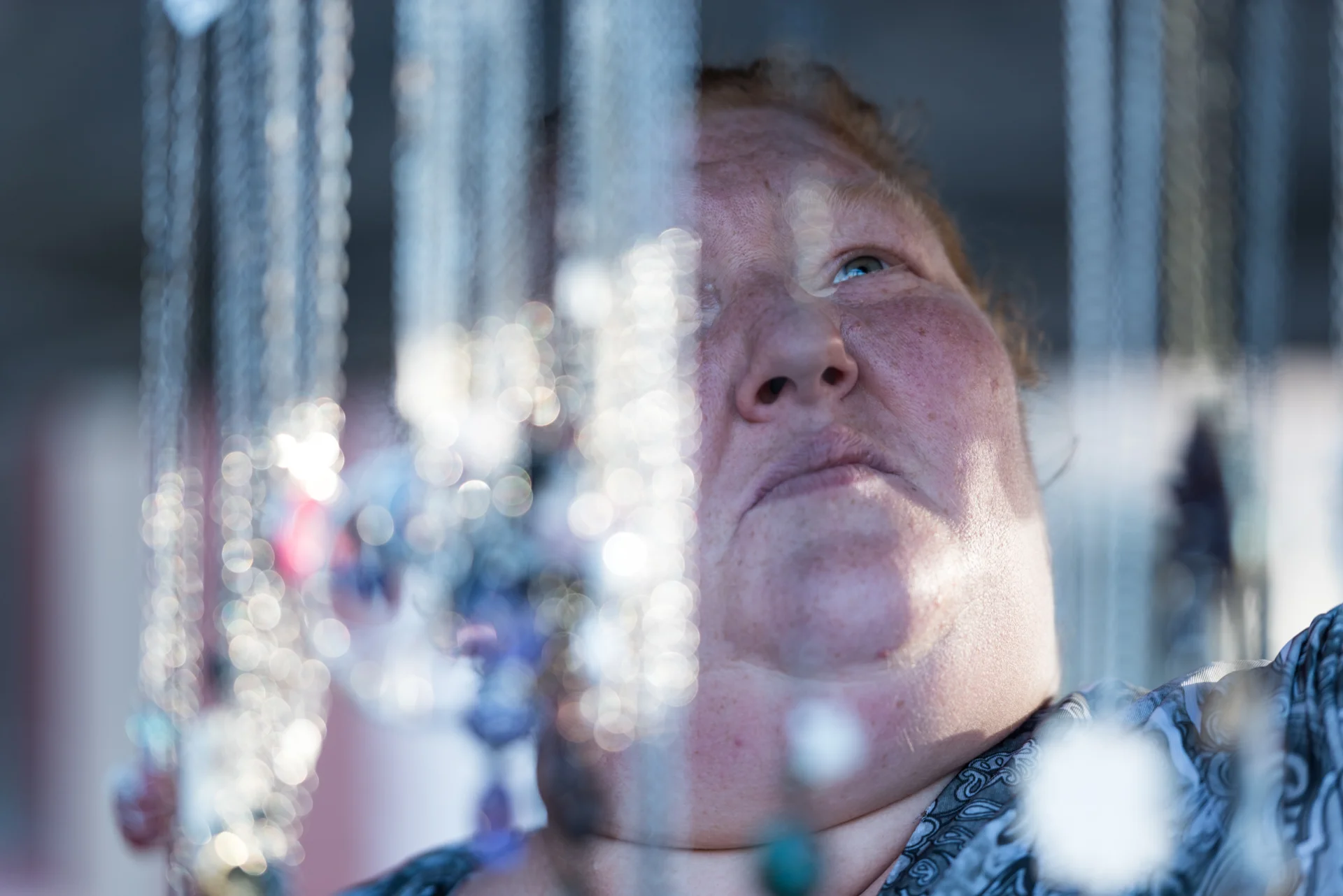 Sarah Perkins hang her handmade jewelry to sell in her booth at a Nelsonville street fair. She said her jewelry making is her family's only source of income, as well as one of her passions.