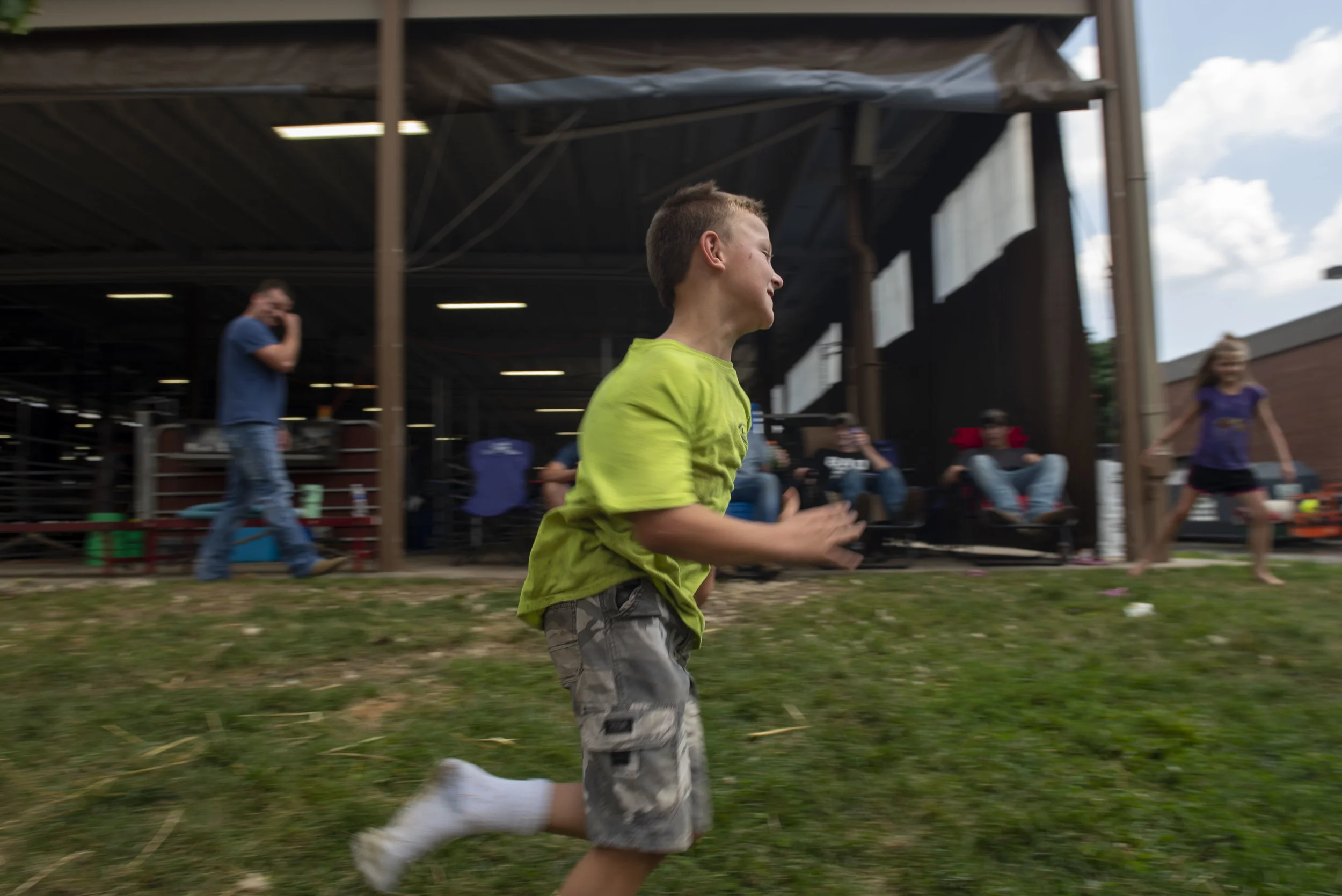  Children play outside of the sheep barn while their family watches. 