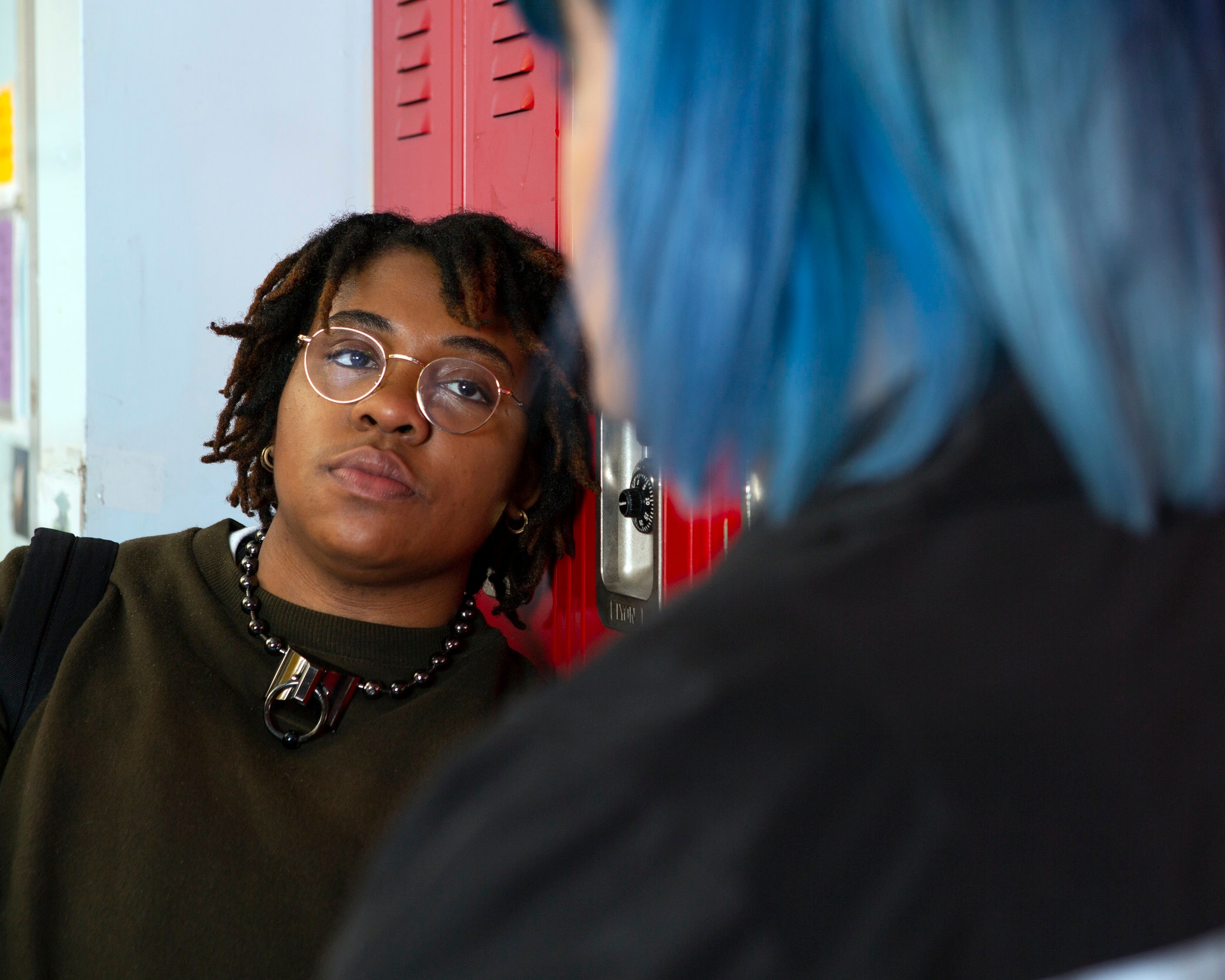 A+non-binary+student+talking+to+a+friend+in+front+of+their+locker.jpg