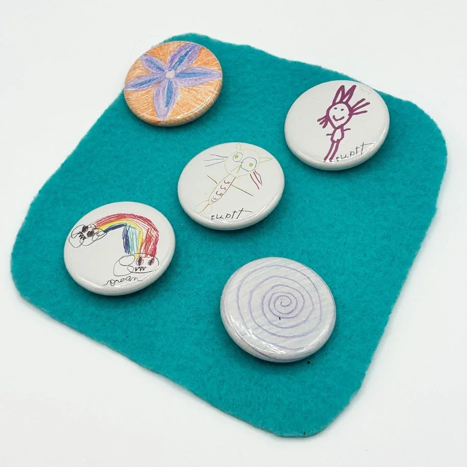 Colorful earrings featuring cartoon mermaid and robot characters on orange background.