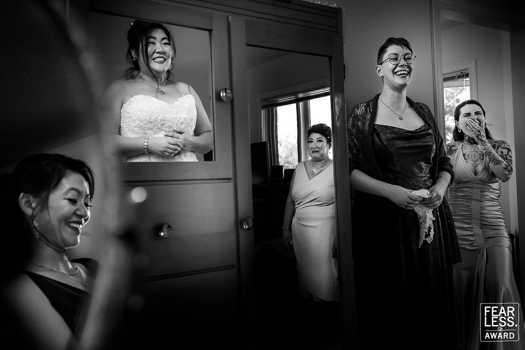 Fearless Award winning black and white wedding photo of the bride getting ready, surrounded by emotional and joyful reactions from family and friends before her McMichael Canadian Art Collection wedding.