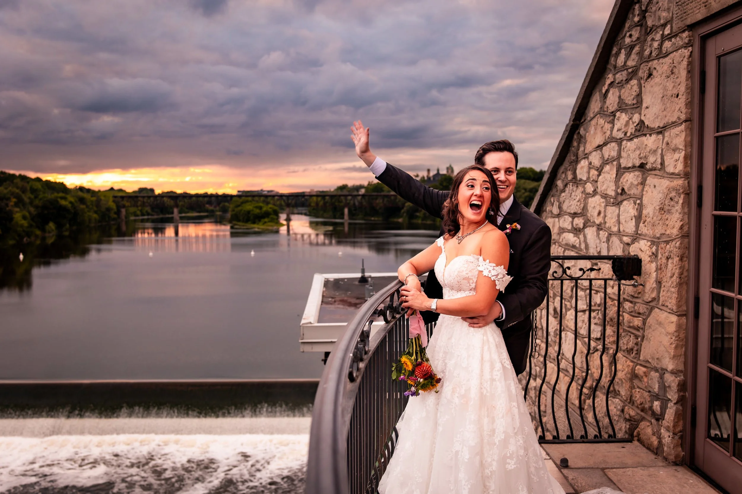 Bride and groom on the balcony at Cambridge Mill during sunset with river views in the background