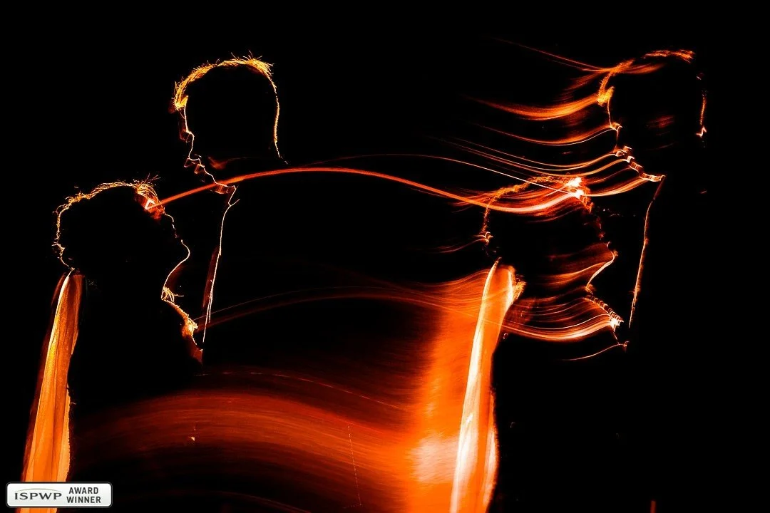 Award winning creative nighttime wedding photo at McMichael Canadian Art Collection, showing a bride and groom in silhouette with orange light painting during their fall wedding portraits by Diego Moura Photography.