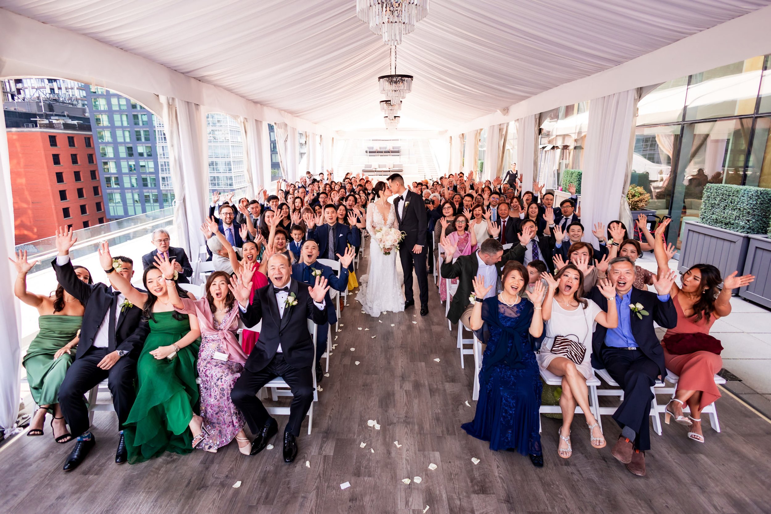 Terri and Jeremy kissing during their Malaparte wedding ceremony in downtown Toronto, surrounded by cheering guests under a white tent with city skyline views