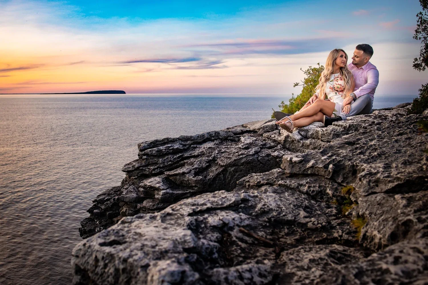 Engaged couple relaxing with their dog on the rocky Georgian Bay shoreline at sunset near Tobermory and the Bruce Peninsula.