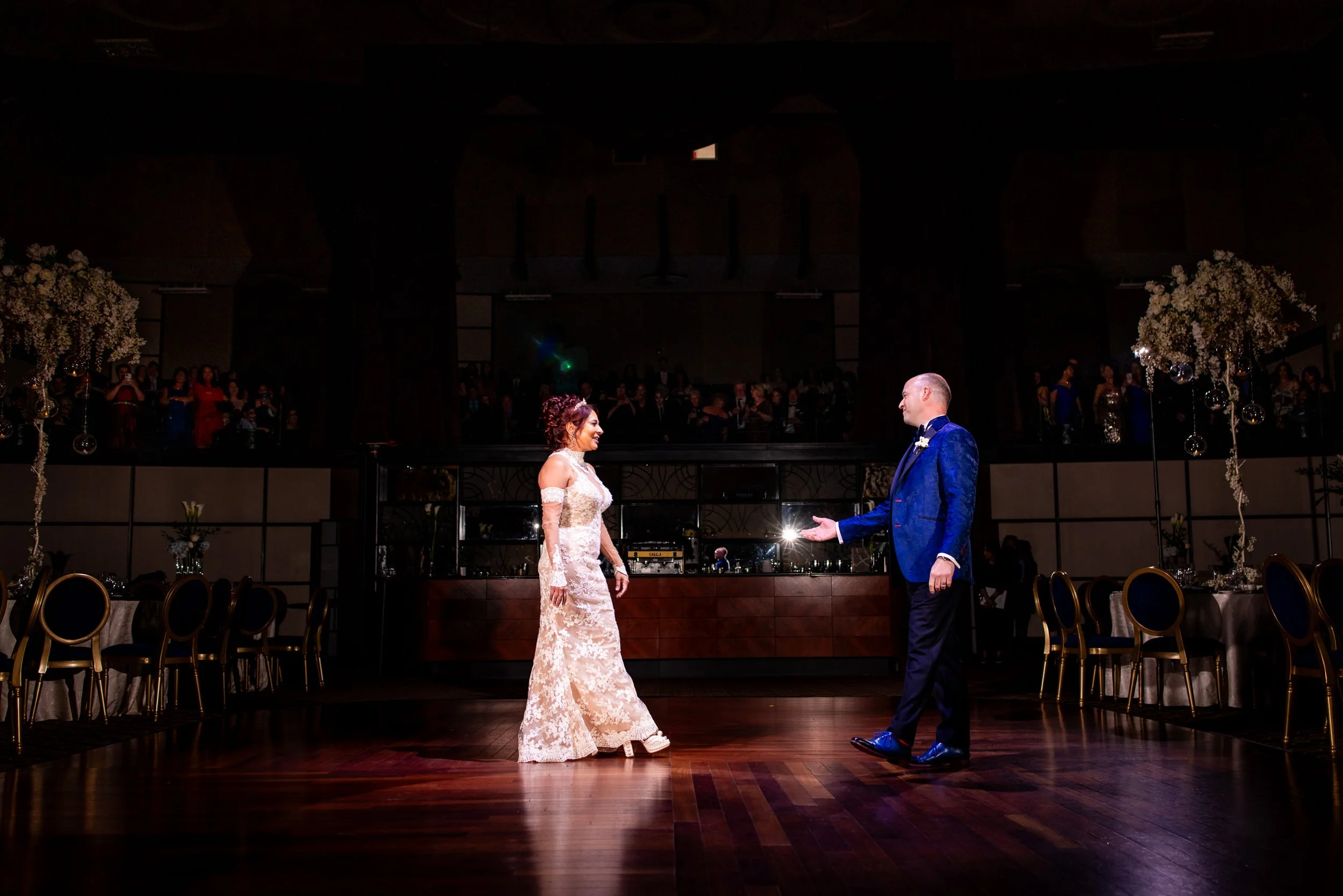 Bride and groom share an emotional moment as they begin their first dance at The Eglinton Grand, with guests watching from the upper balcony of the elegant art deco venue.