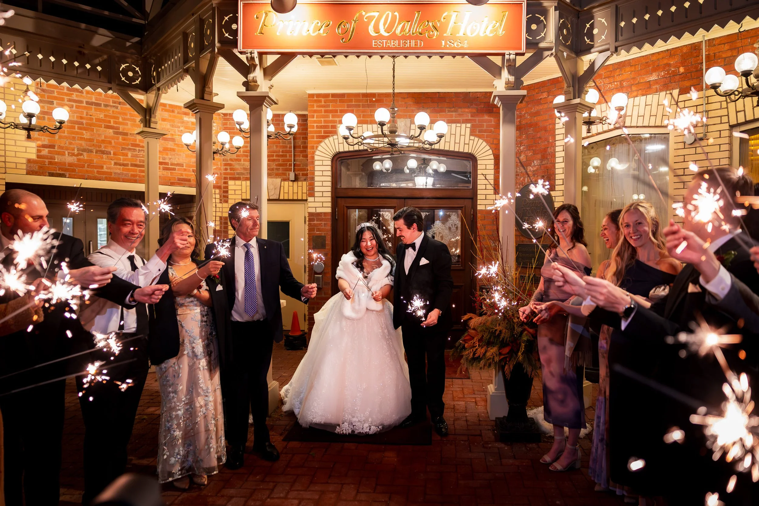 Bride and groom celebrating with guests during a sparkler exit outside Prince of Wales Hotel in Niagara on the Lake after their Valentine’s Day wedding