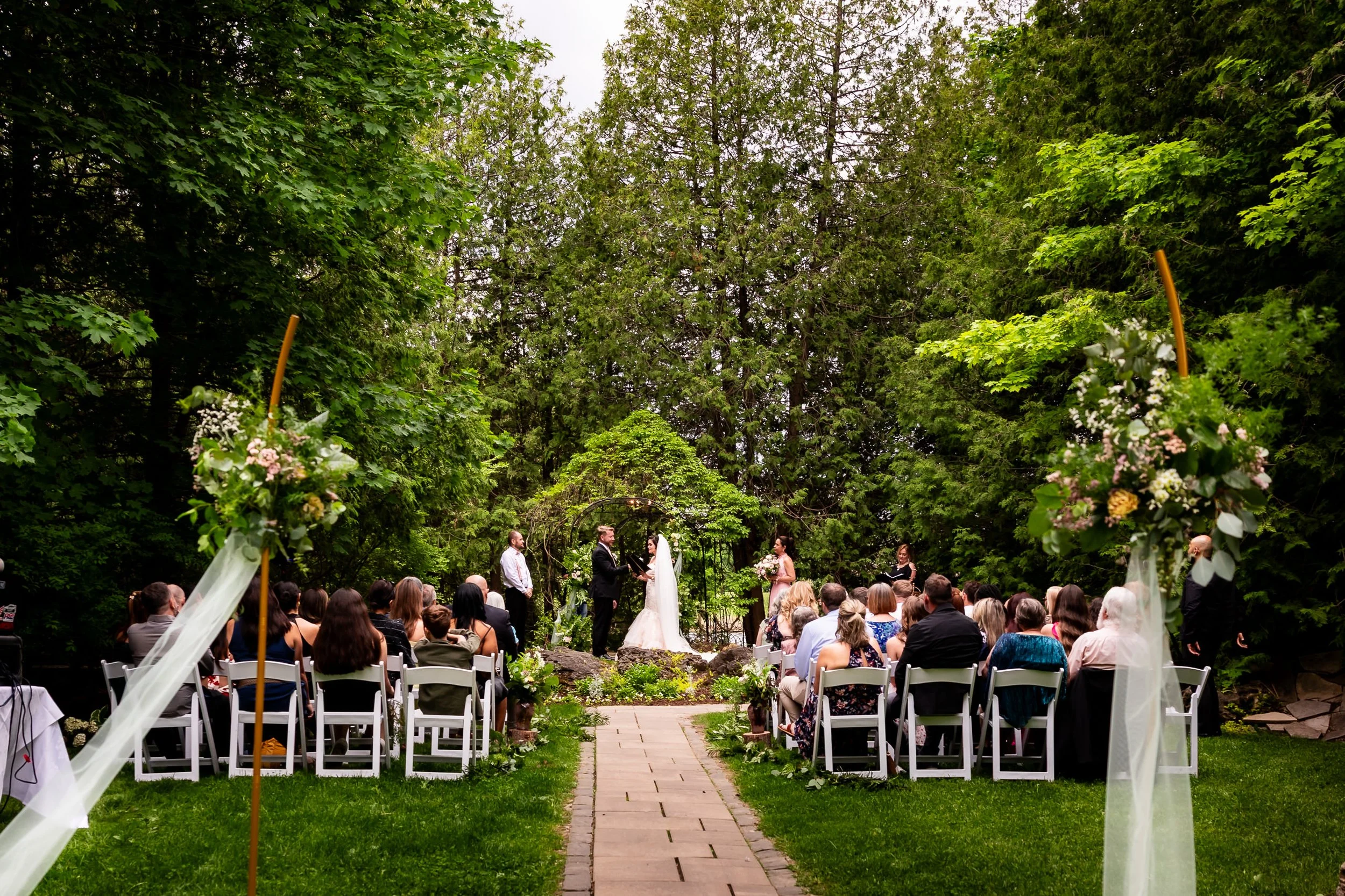 Cecilia and Darren exchanging vows during their outdoor garden wedding ceremony at The Millcroft Inn in Alton, Ontario.