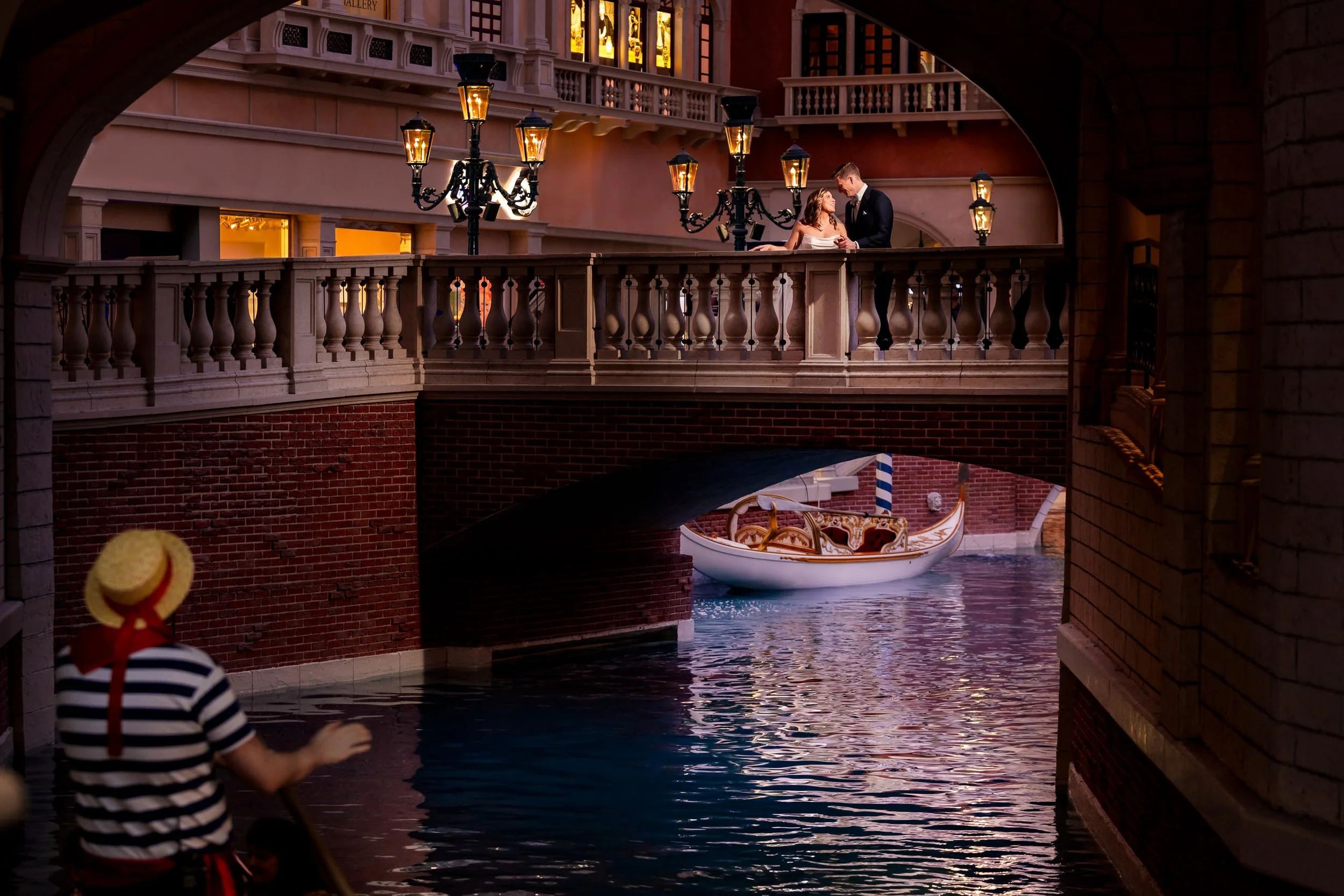 Bride and groom share a romantic moment on a bridge at The Venetian Las Vegas, with canal water, gondola, and warm evening lights creating a cinematic destination wedding portrait