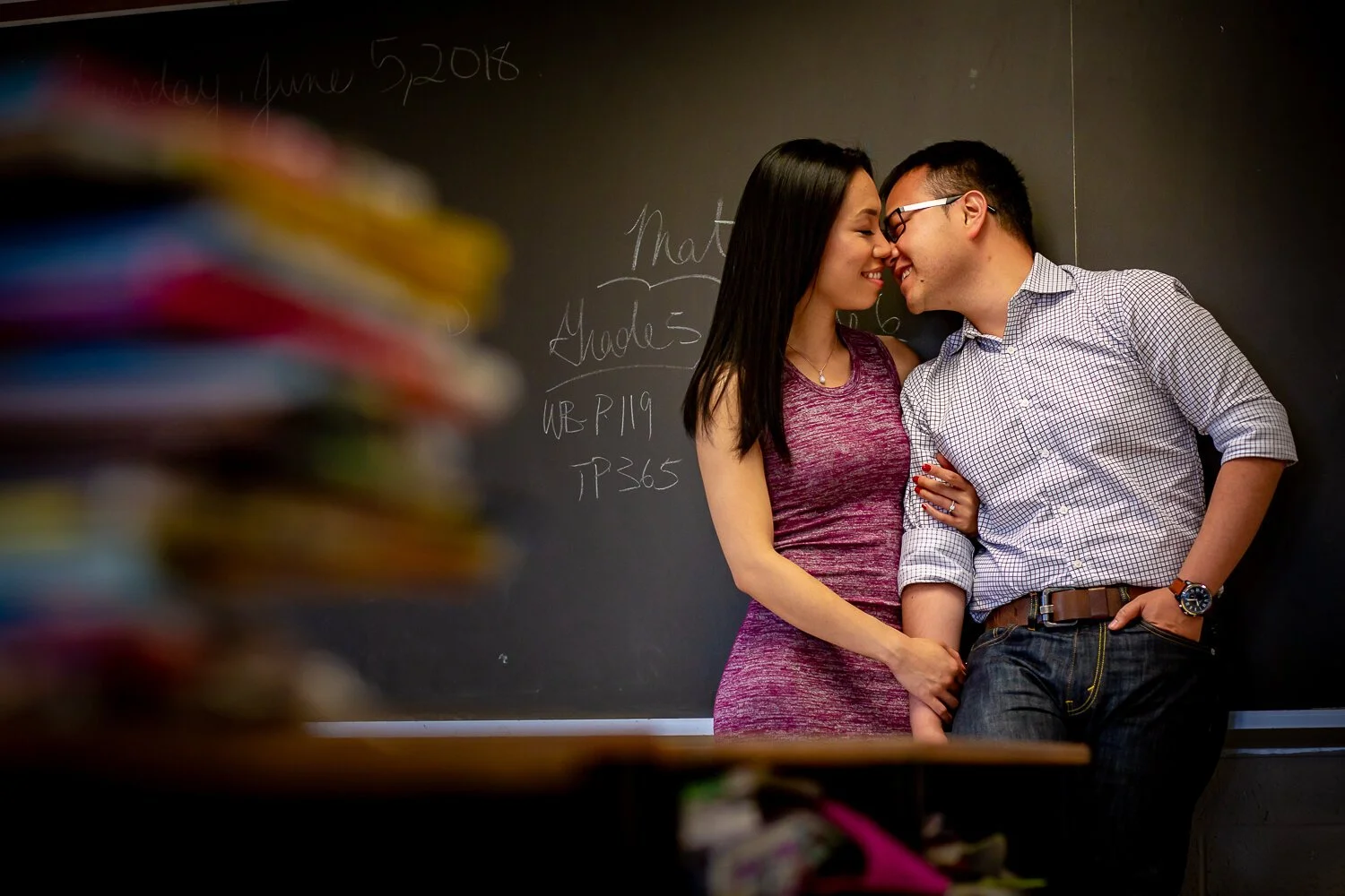 Engaged couple sharing a sweet moment in a classroom during their school-themed engagement photo session in Toronto.