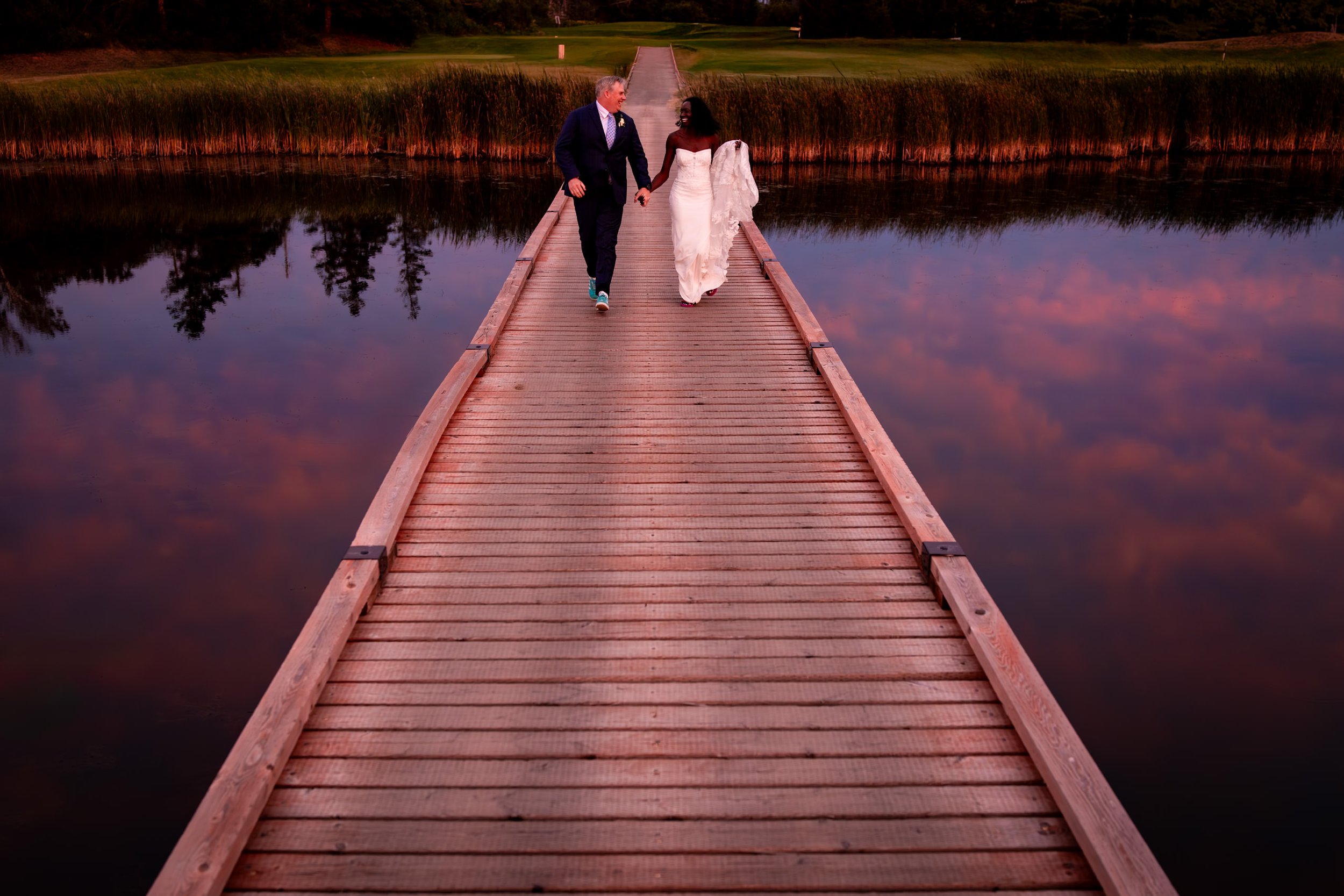 Anita and Alex walking hand in hand across the bridge at Rodd Crowbush Golf & Beach Resort during their next day PEI wedding photo session.