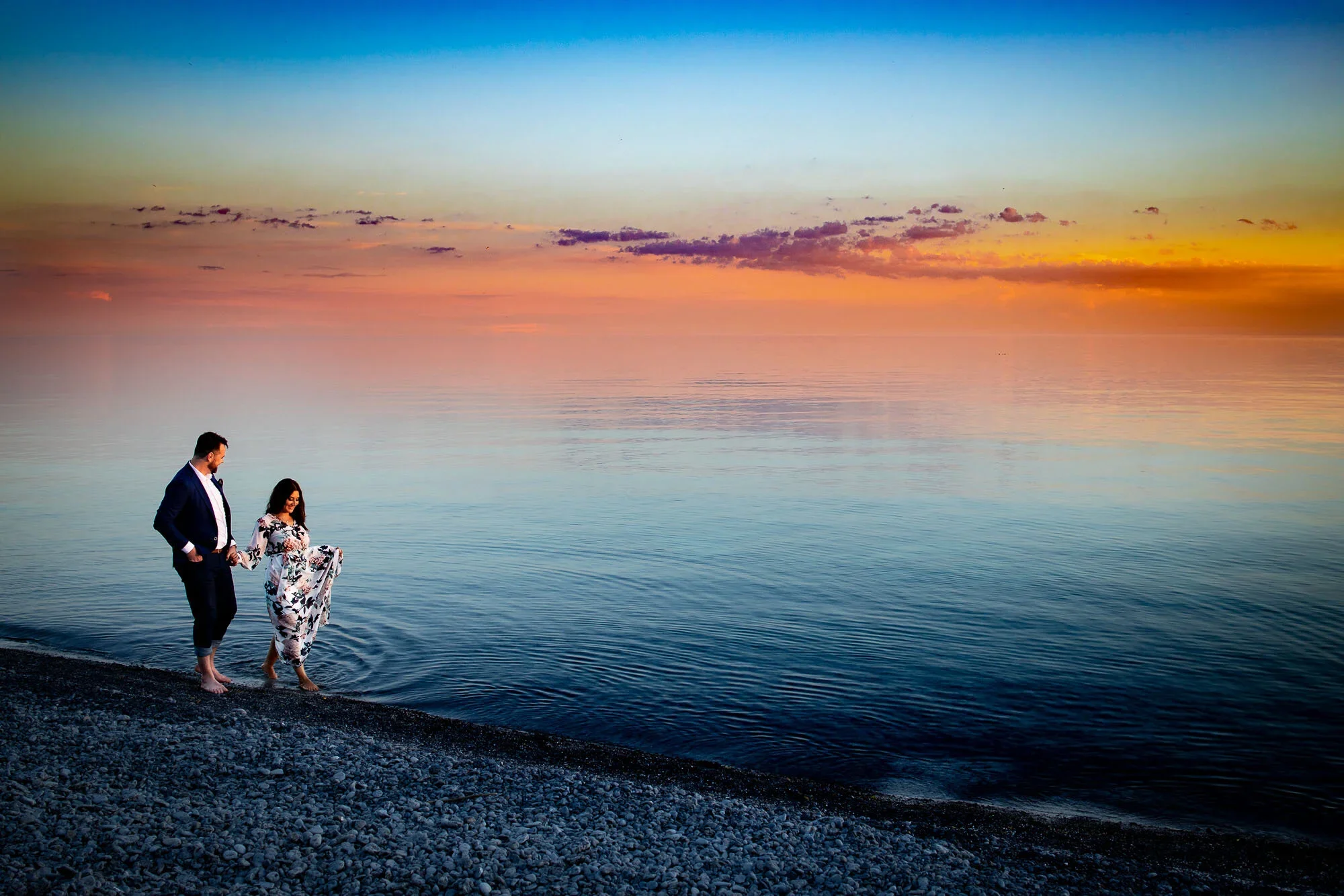 Prince Edward County engagement photos of a couple walking along the shoreline at sunset during a relaxed and romantic Ontario engagement session.
