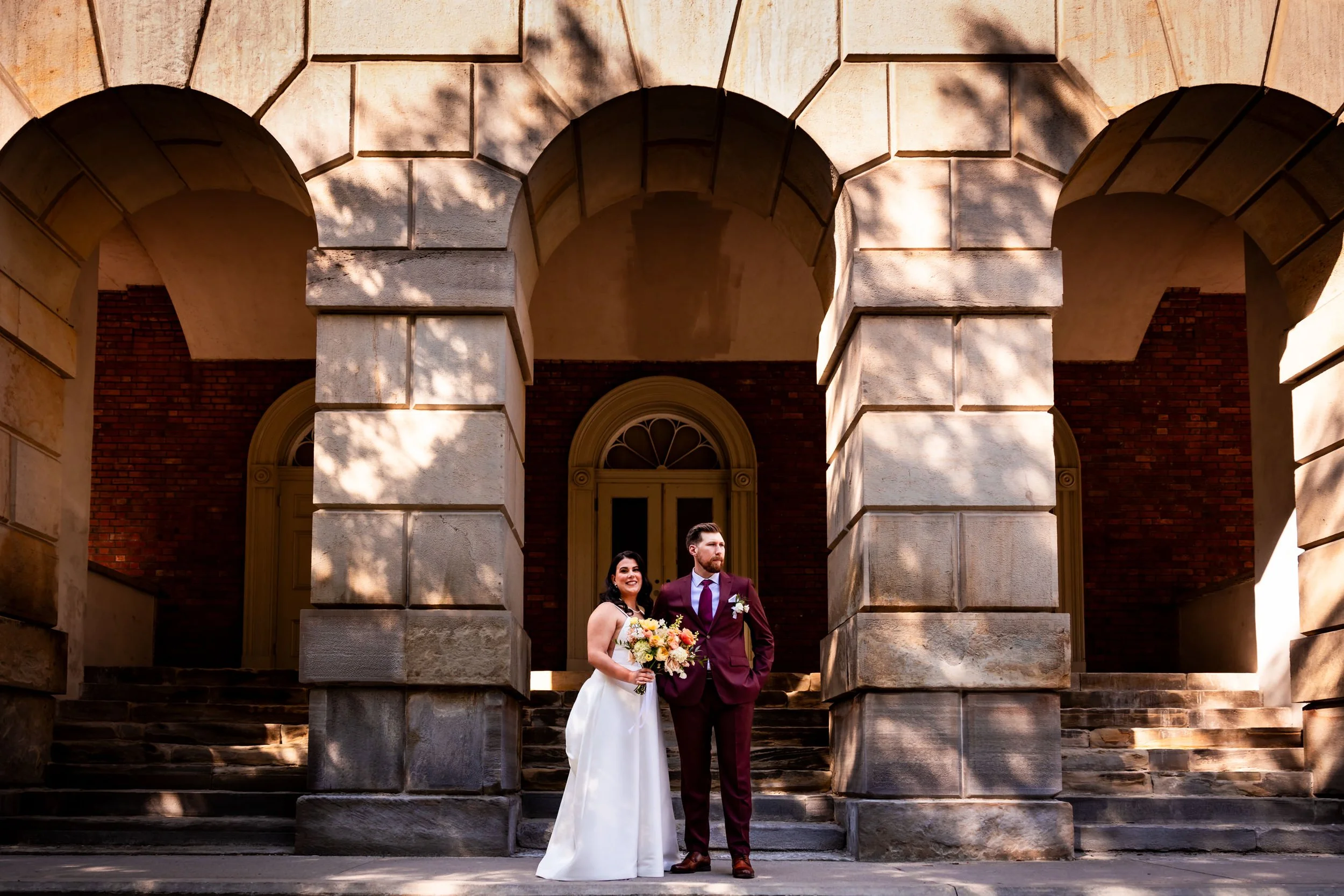 Bride and groom posing under the stone arches at Osgoode Hall in downtown Toronto before their Eglinton Grand wedding reception.