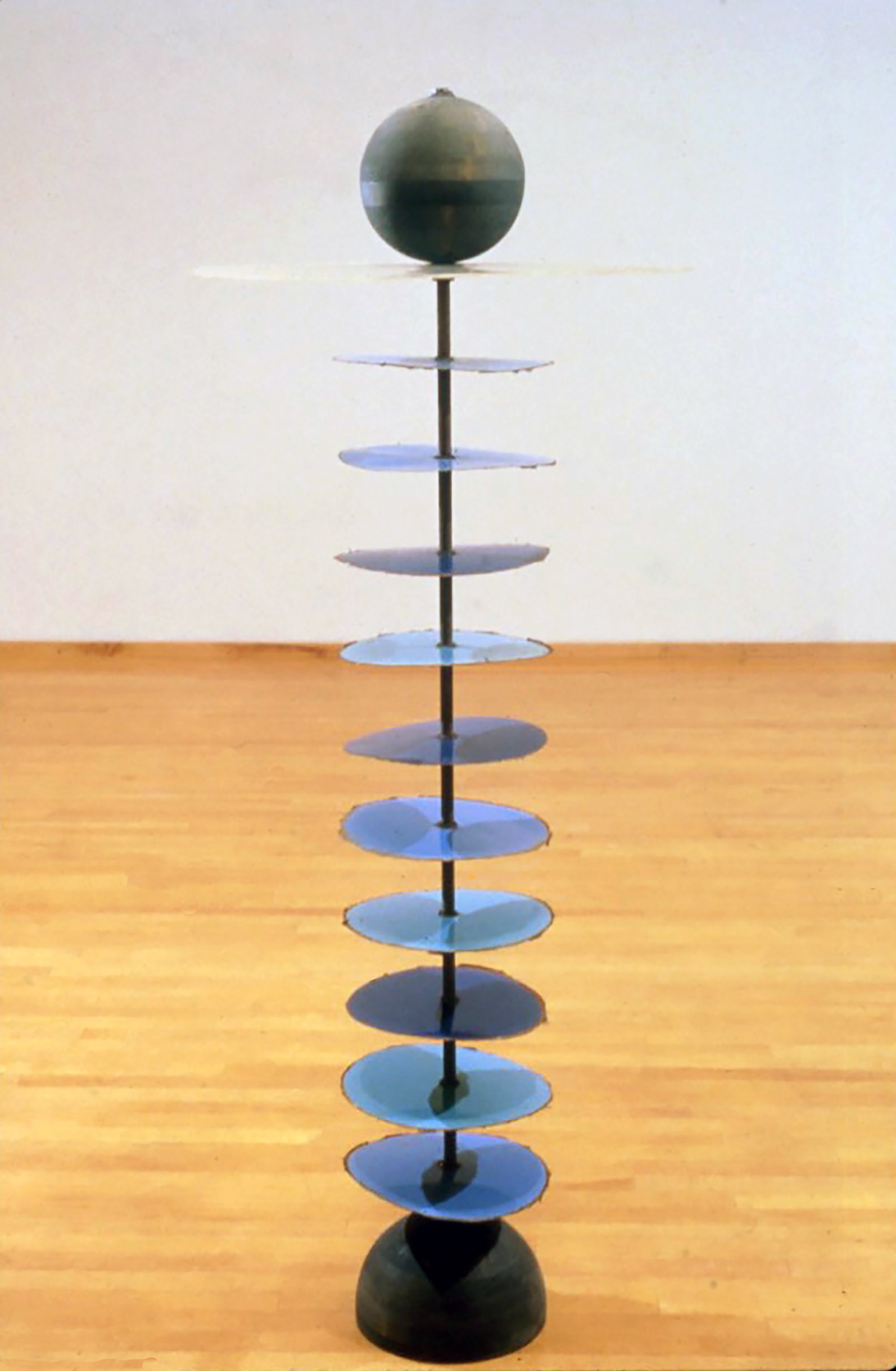  Head Spin, 1993, fiberglass resin, steel and wood  In Head Spin, a series of metal disks strung along a human-sized metal spine is topped with a large fiberglass plate that proffers a featureless wooden head as if it were John the Baptist’s on Salom