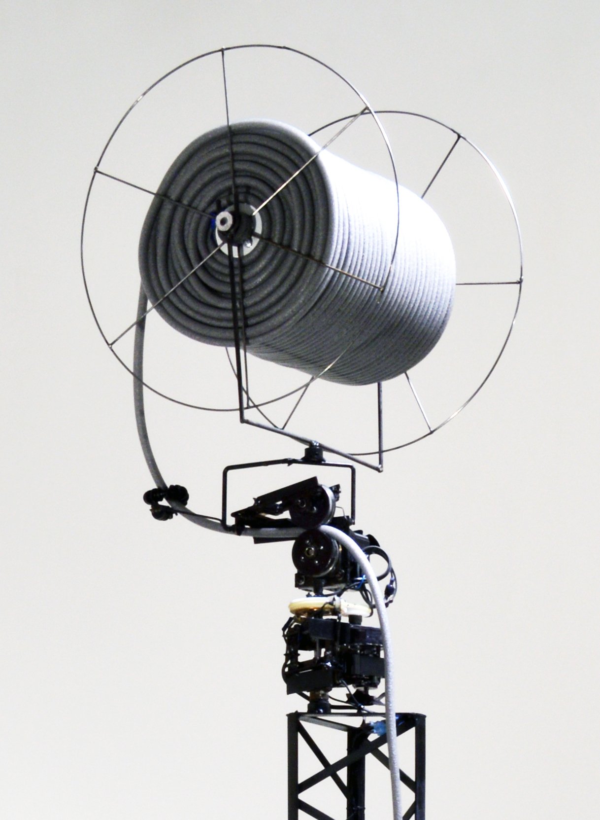  Host (2018), detail, one of six backer rod spools, steel with motor, foot pedal and timer, freestanding kinetic sculpture: 15 feet tall, variable 6 foot diameter pile unspools at base 
