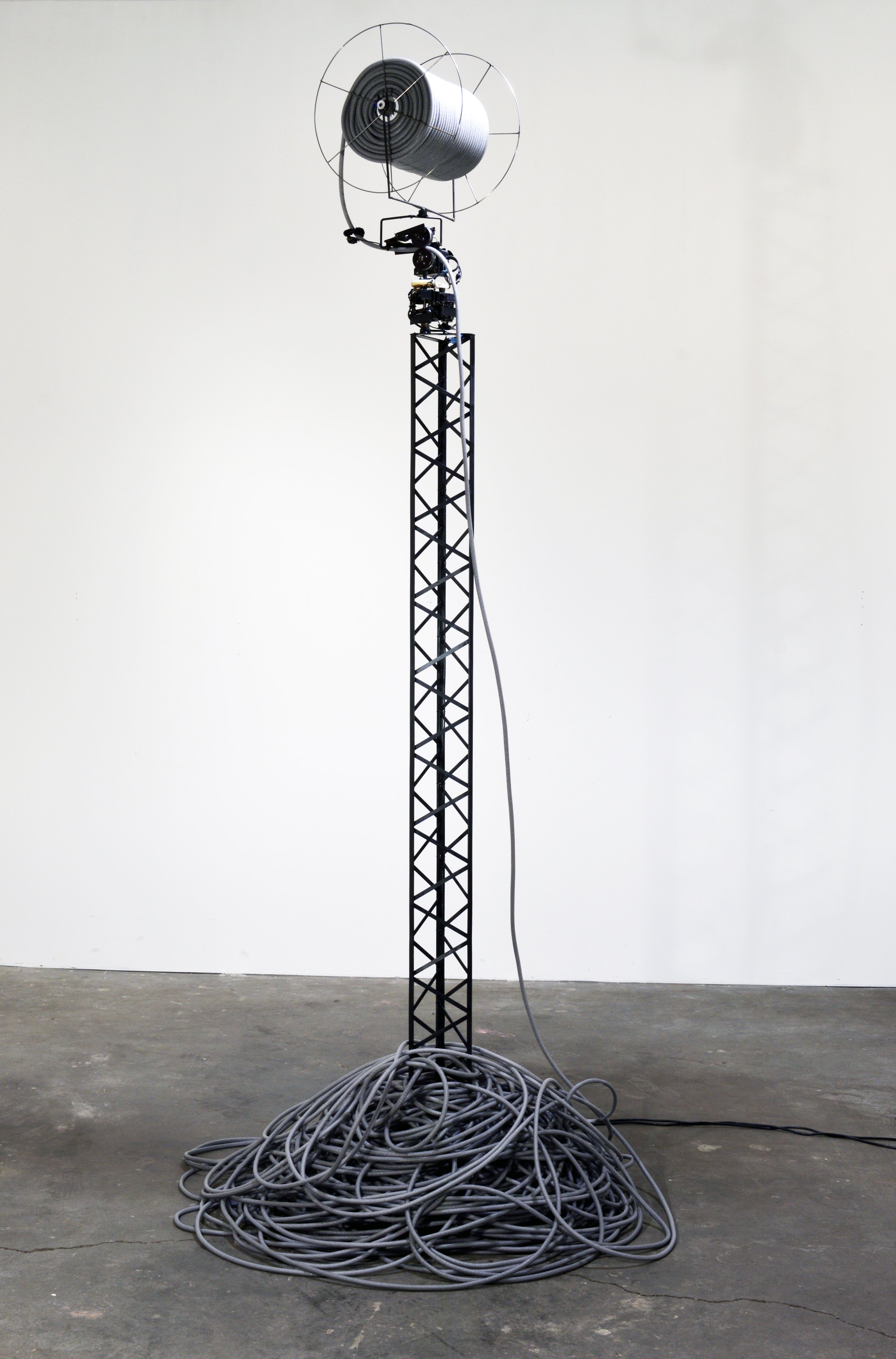  Host (2018), steel with motor, backer rod, foot pedal and timer, freestanding kinetic sculpture: 15 feet tall, variable 6 foot diameter pile unspools at base 