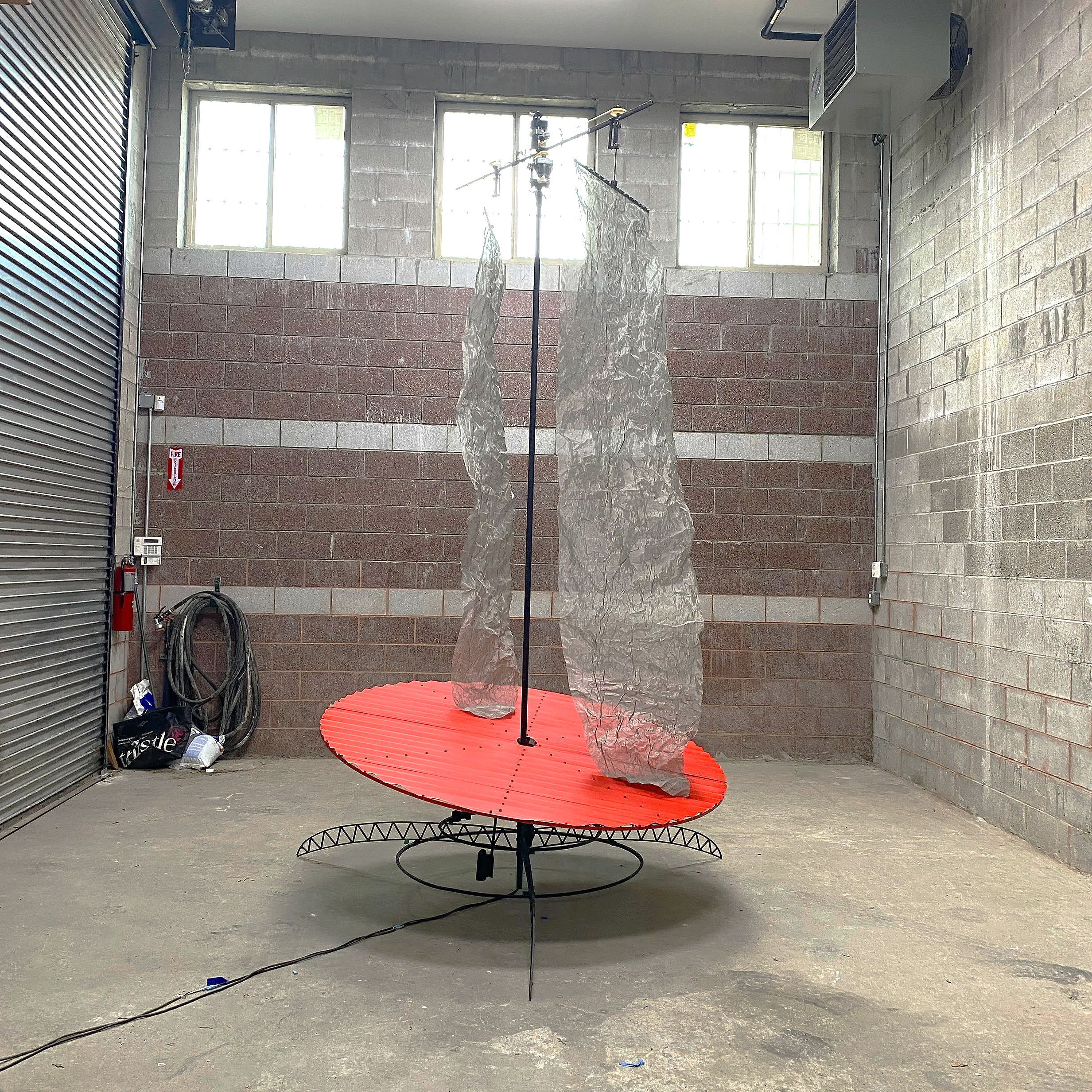  Agreeing (2024) is a freestanding 15 foot steel sculpture made over the course of one  year.  Swaths of steel mesh oscilate around a central column. Their lengths differ, and cause a red steel disc to oscilate over a weighted gimble. Wavy movements 