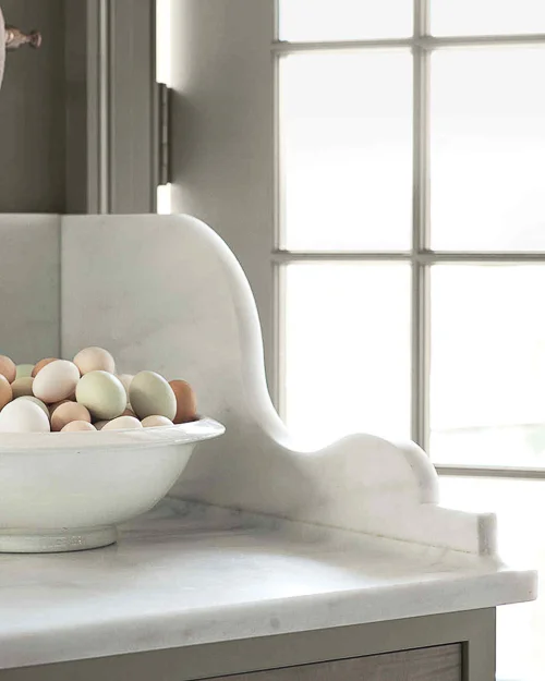 Martha Stewart created this beautifully scalloped marble edge bracket as a side wall to prevent messy spills when someone enters/exits the adjacent door. Beautiful Kitchen Marble Ideas.