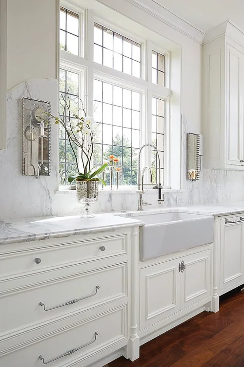 A marble slab, applied to the wall around this window, gracefully arches upward to play host to two mirrored sconces. See more mesmerizing Kitchen Marble Ideas to use in your next kitchen.