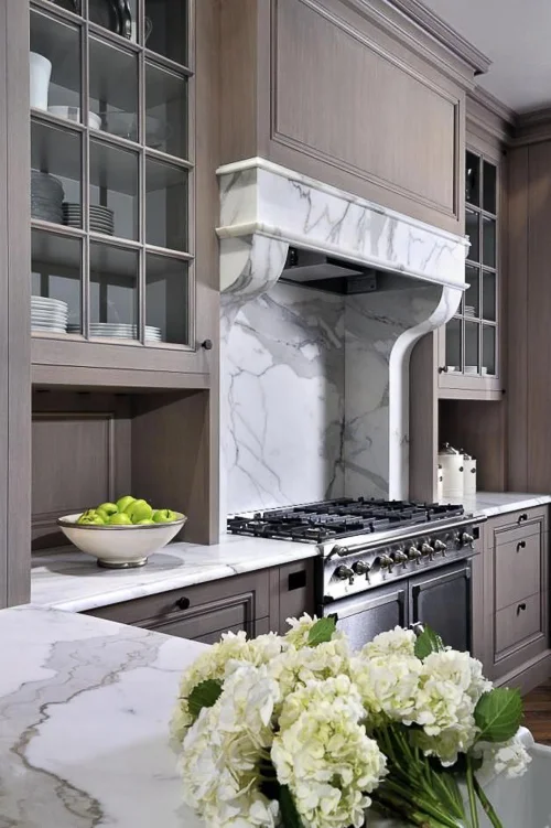 While marble range hoods are trending, they are typically more contemporary in design. I love this one by Peter Block. It references the lines and character of an Antique Marble Fireplace but is ideally suited to serve as this range hood. Works well with the paneled cabinetry. Kitchen Marble Ideas.