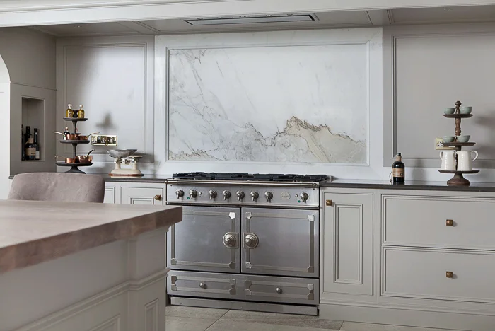 A beautiful marble backsplash behind the Cornu Fe range is complemented by the paneled cabinetry on either side. Kitchen Marble Ideas.