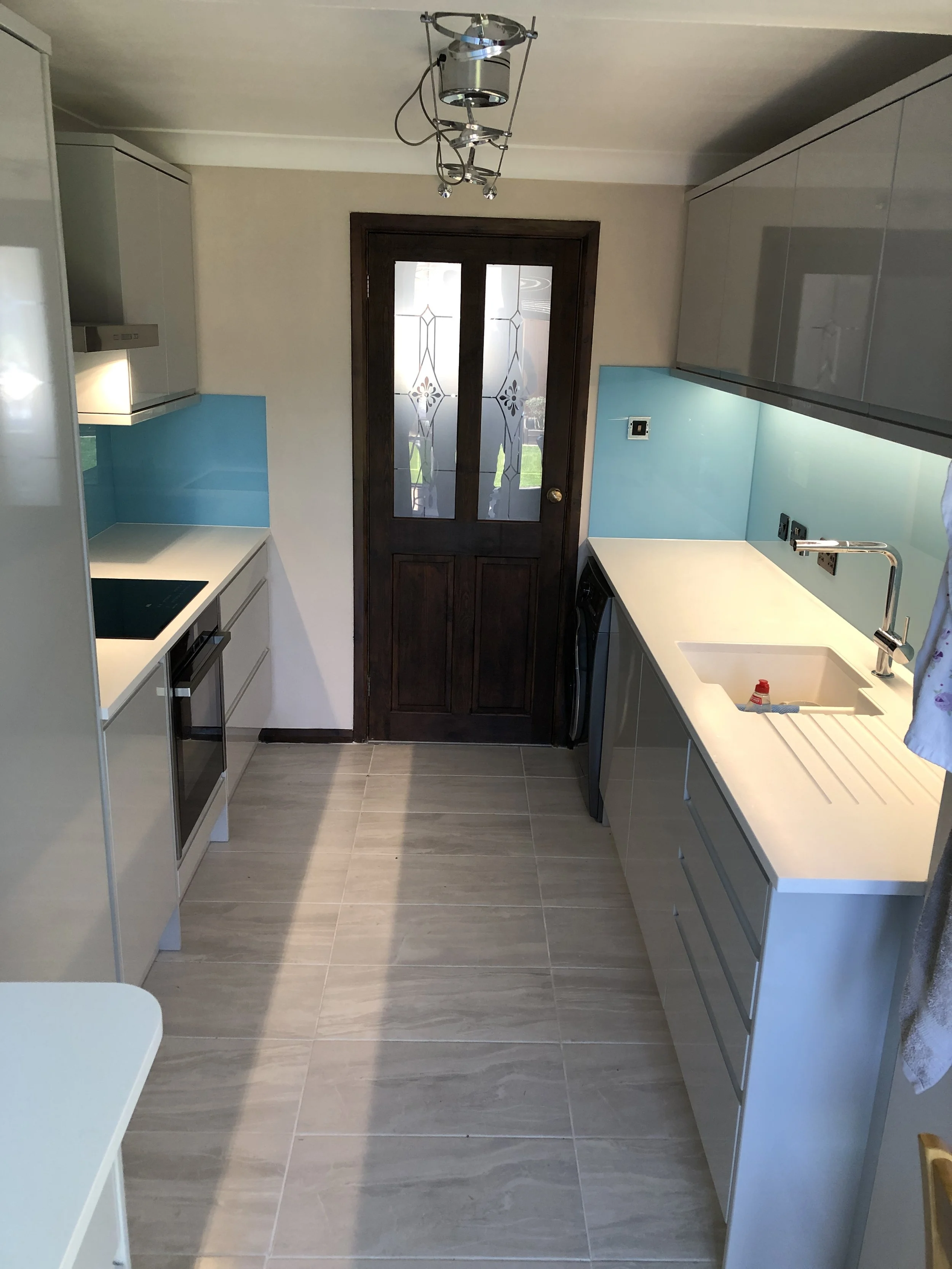 Modern fitted kitchen with custom glass splashback in West Sussex