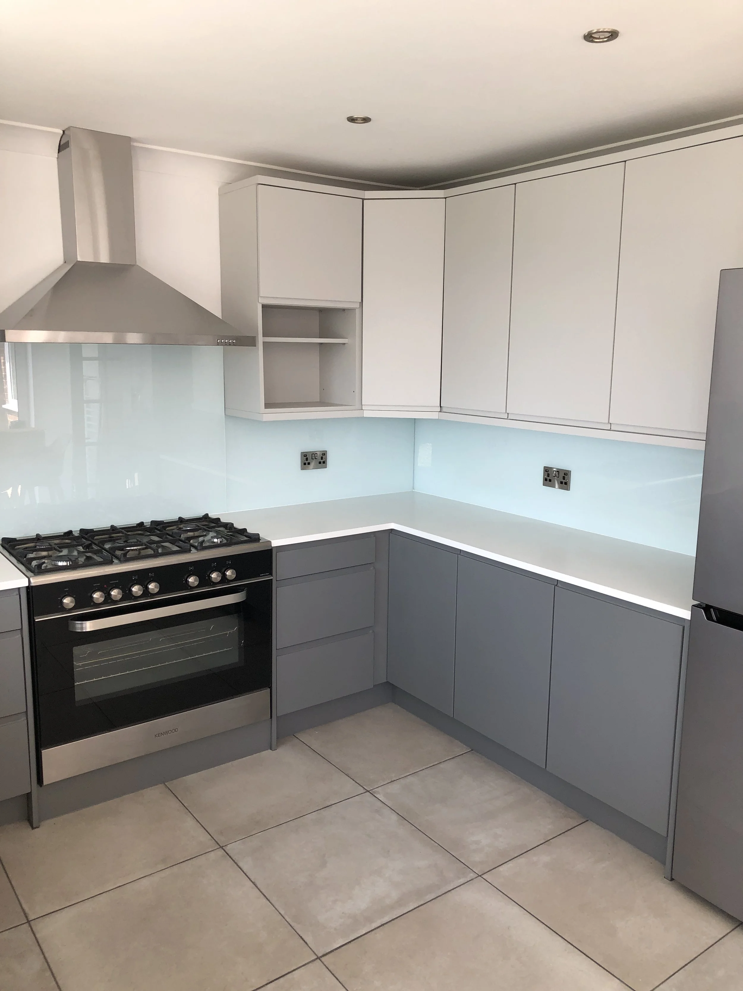 Modern grey fitted kitchen with light blue glass splashback in Shoreham-by-Sea
