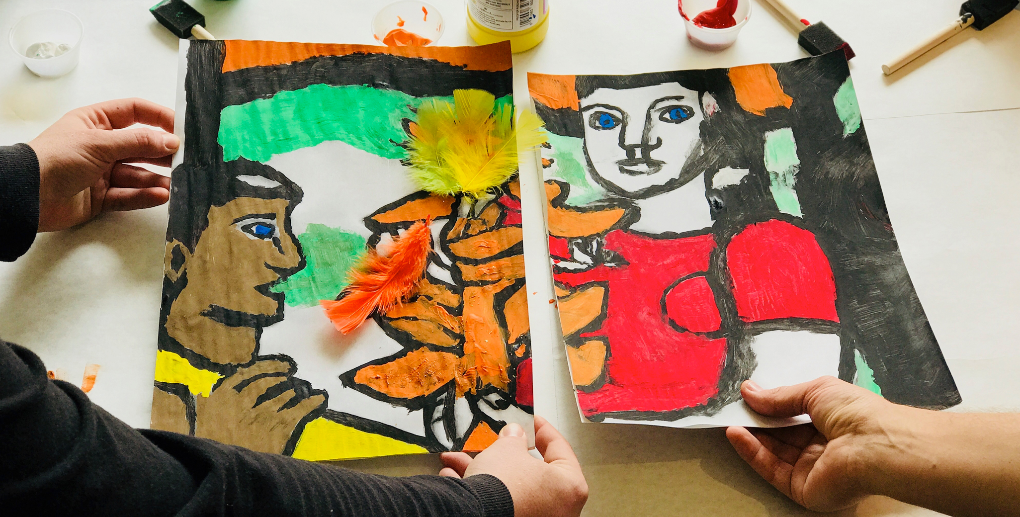 Two participants work to create a mural divided into several sections. 