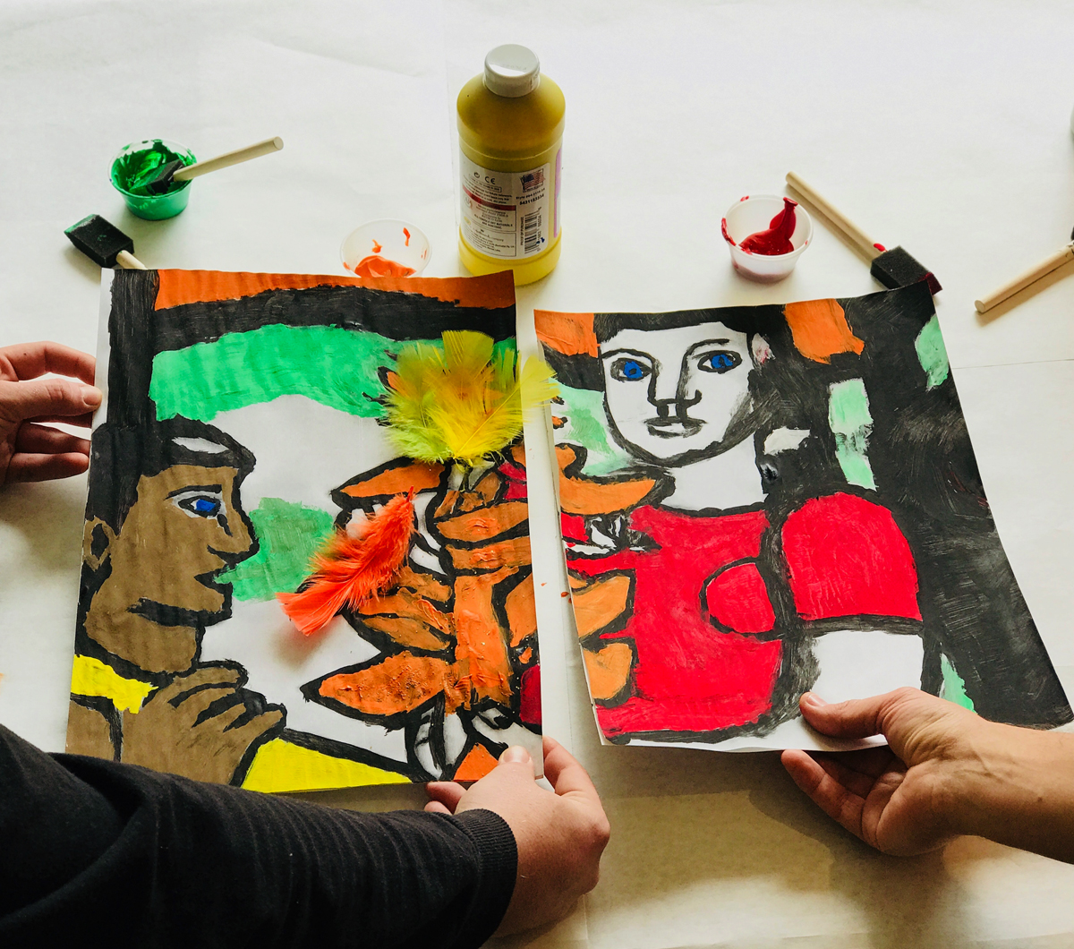 Two participants work to create a mural divided into several sections. 